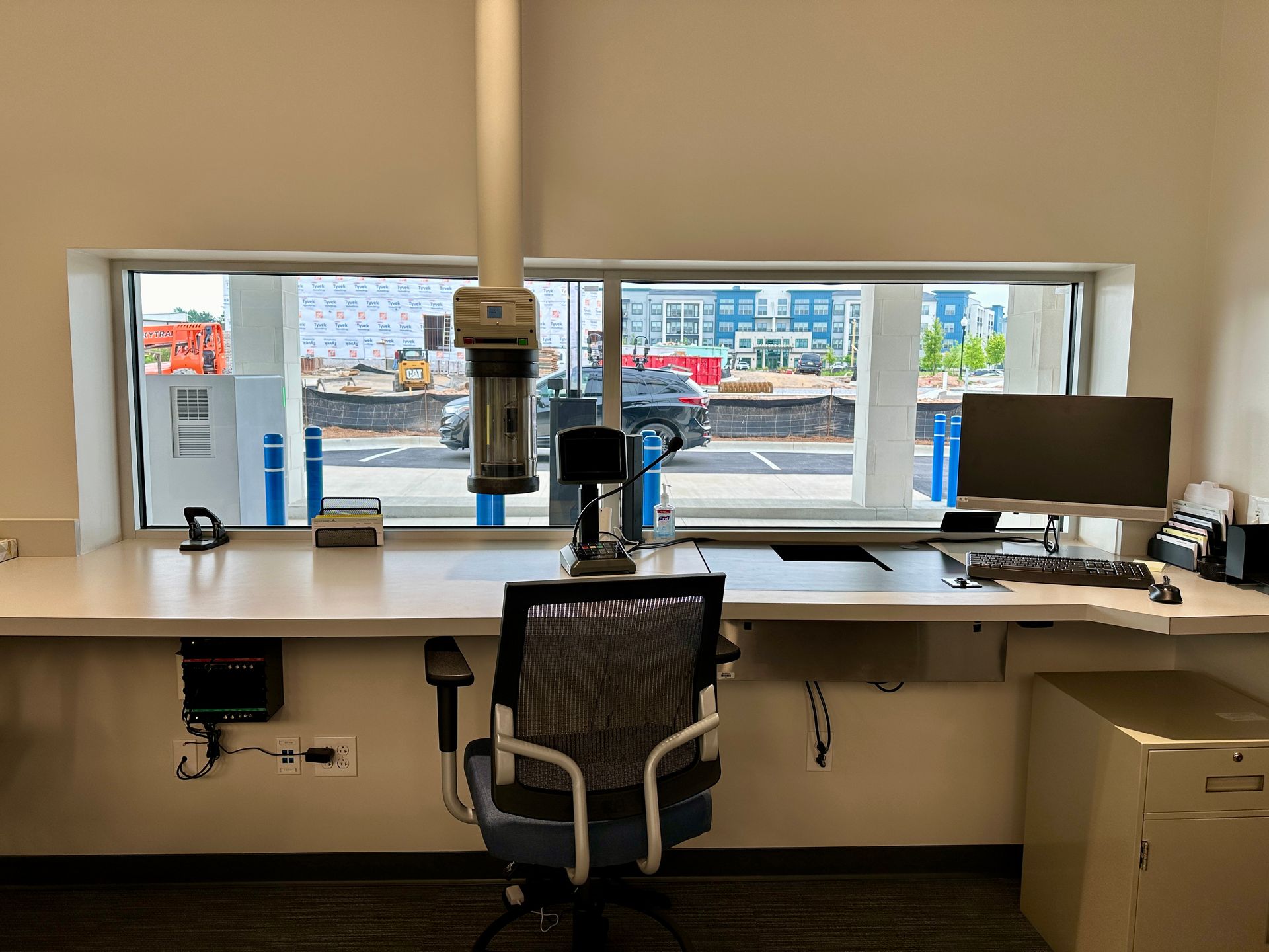 A desk with a computer and a chair in front of a window.