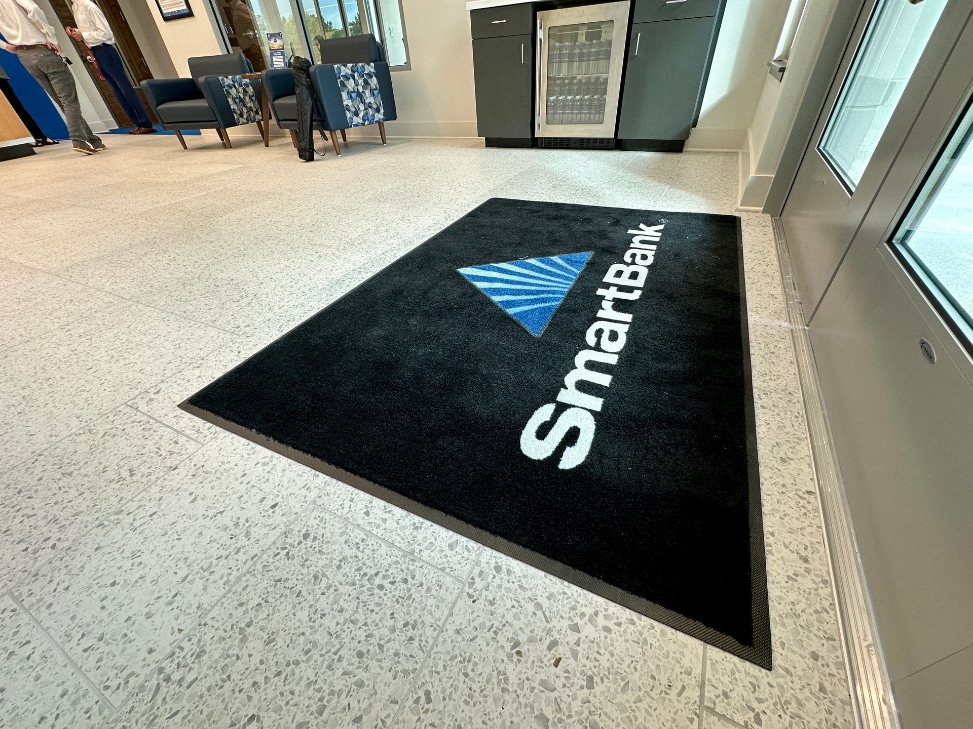 A smartbank logo is on a black mat in a lobby.