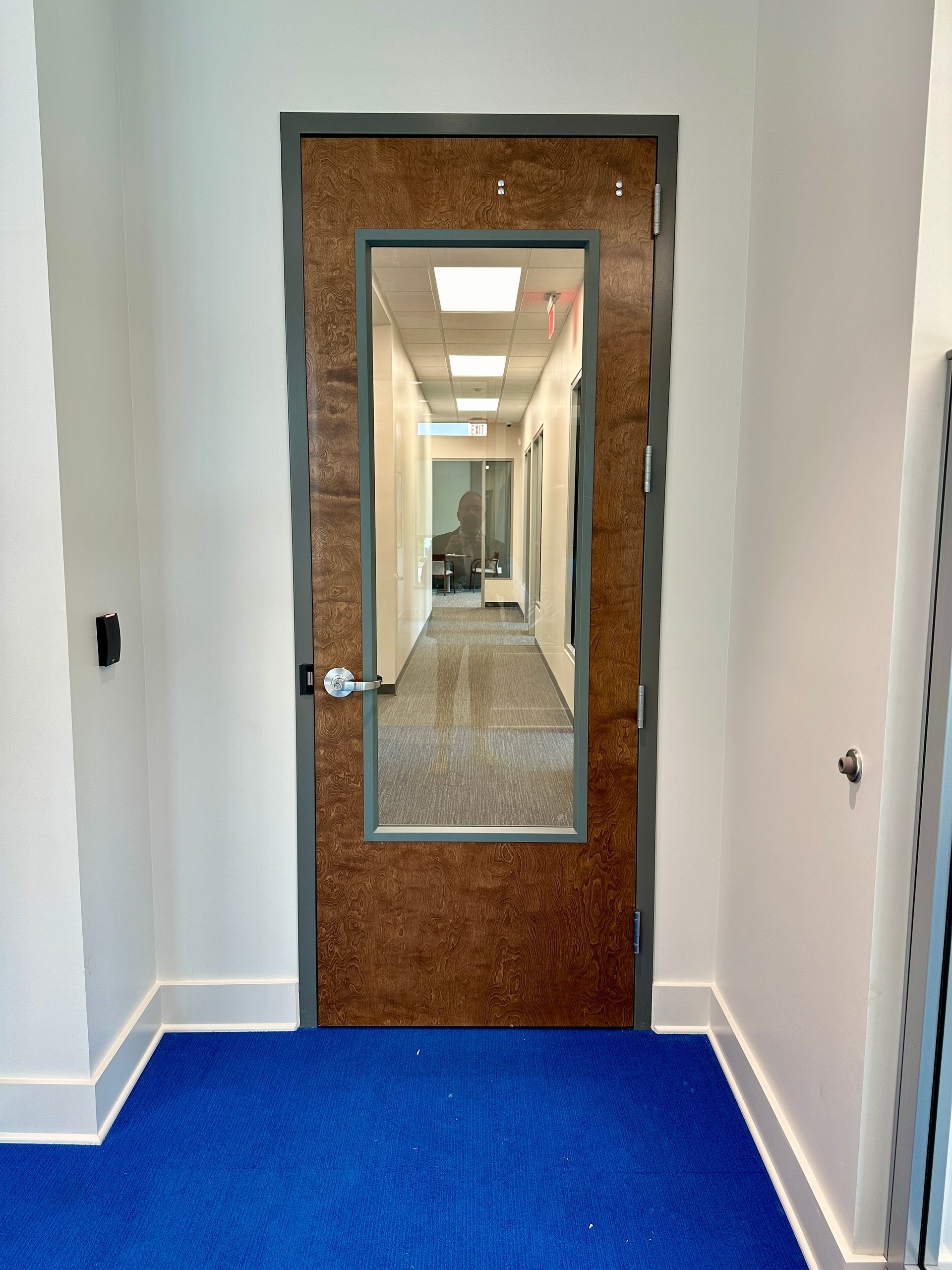 A hallway with a door and a blue carpet