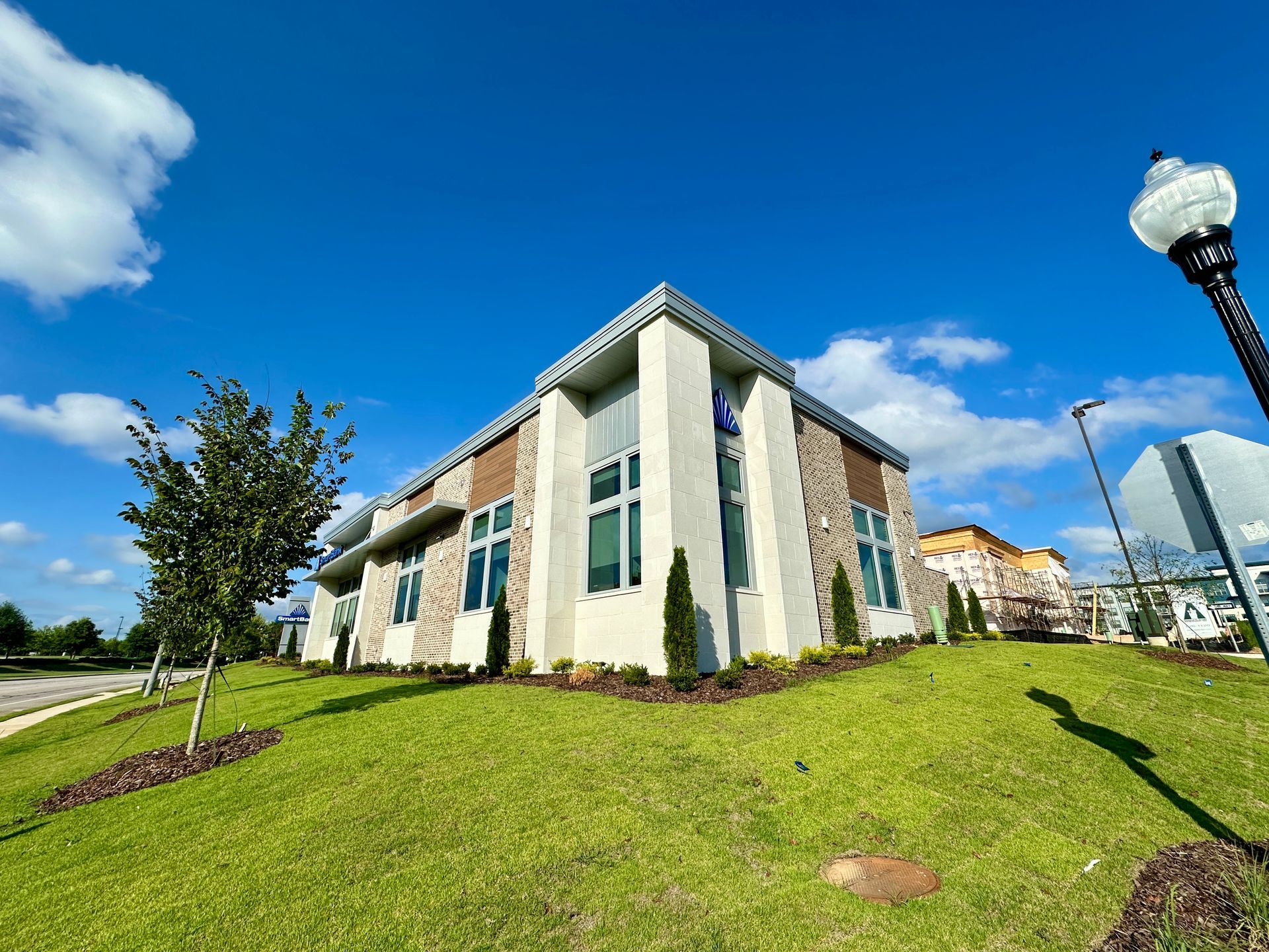 A large white building with a lot of windows is sitting on top of a lush green lawn.