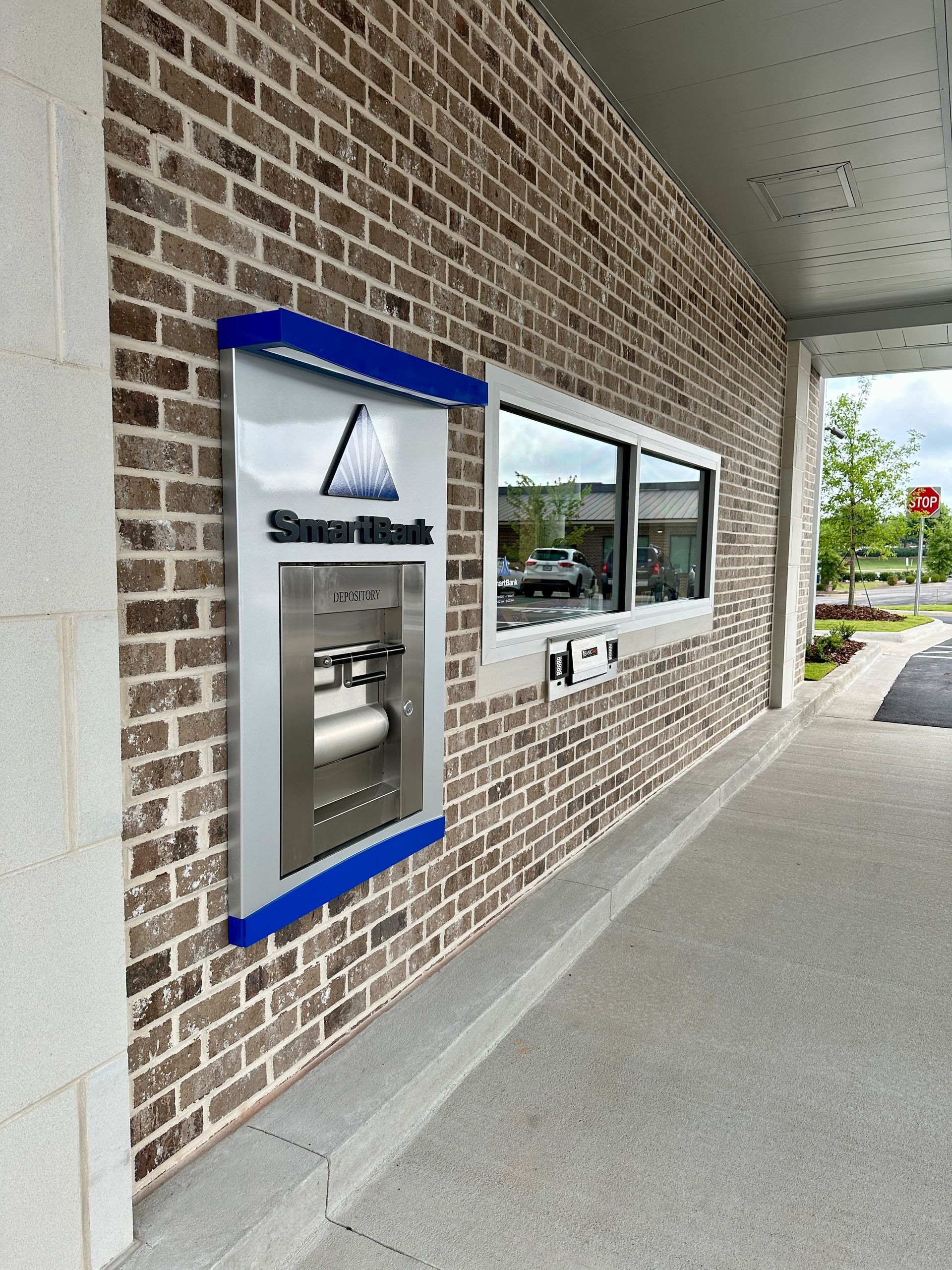 A brick wall with a window and an atm on it.