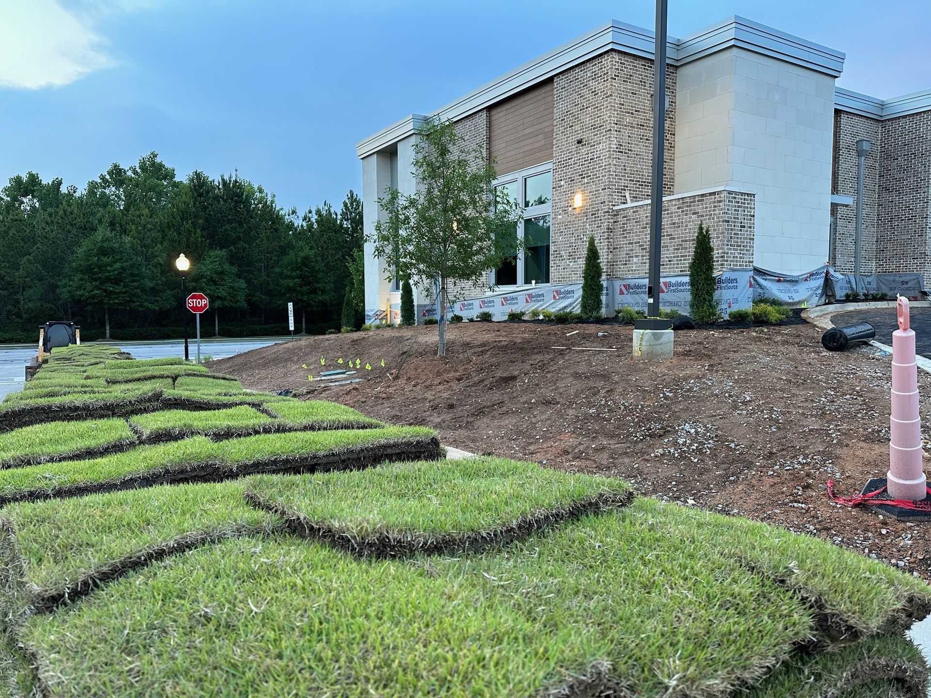 A pile of grass is sitting in front of a building under construction.