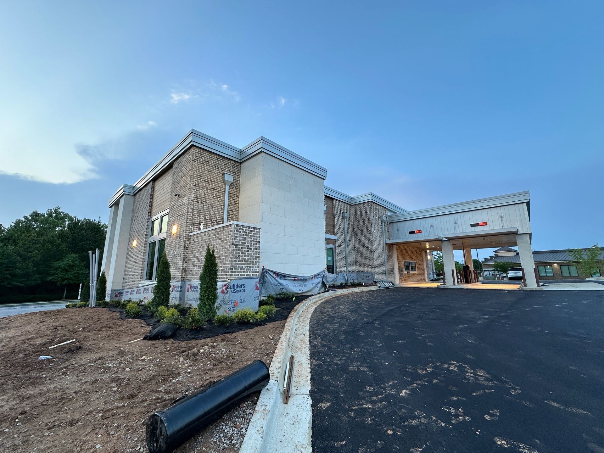 A large white building is sitting on top of a dirt hill next to a parking lot.