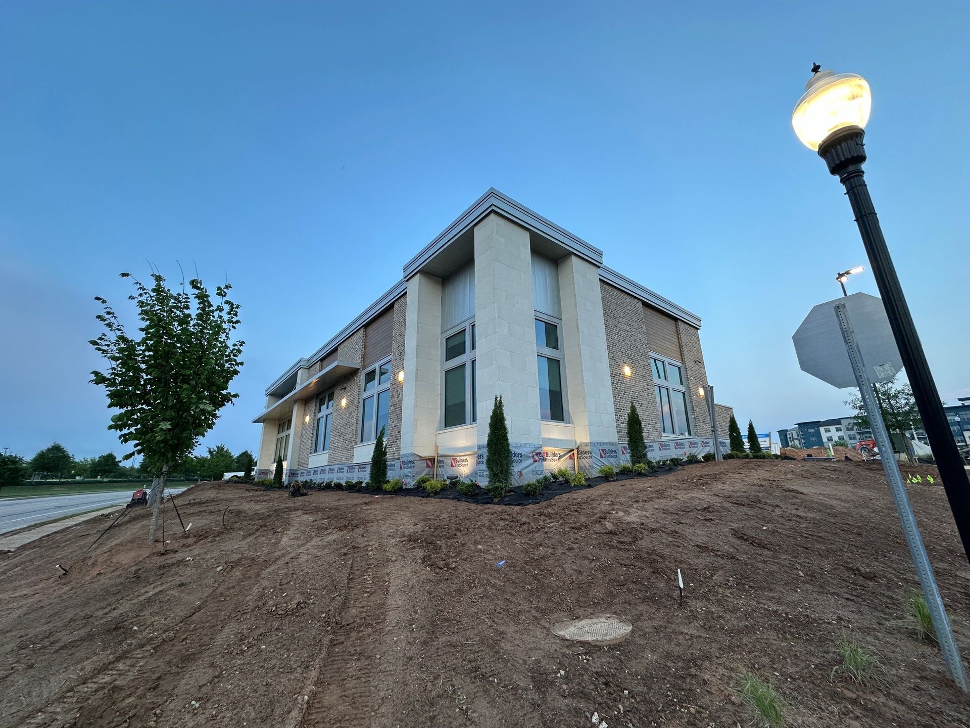 A large building is sitting on top of a dirt hill next to a street light.