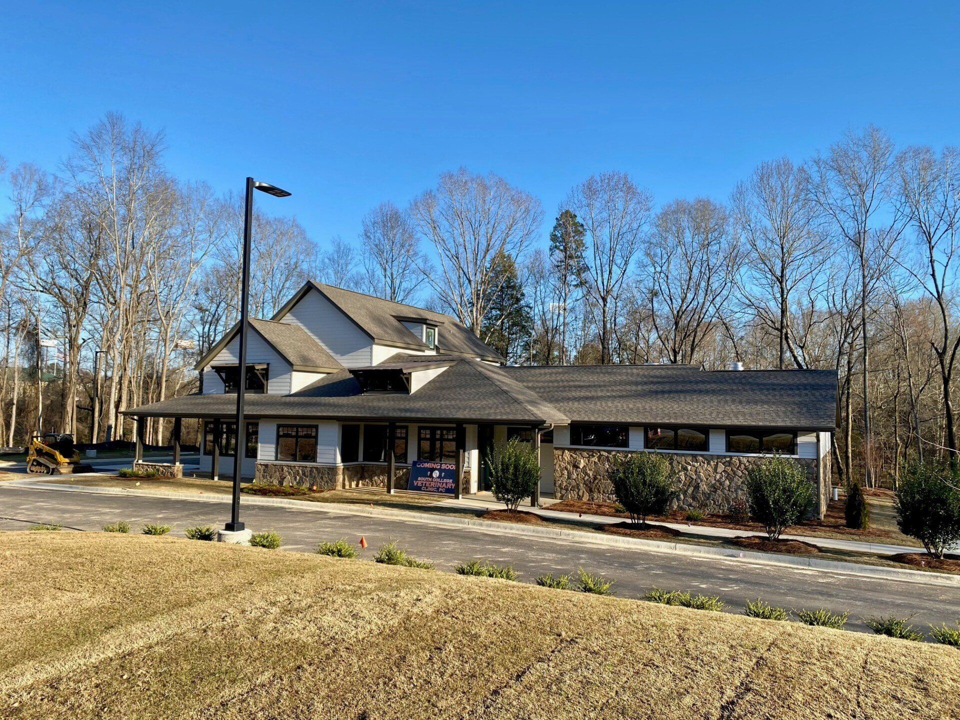 A large house with a lot of windows is sitting in the middle of a field.