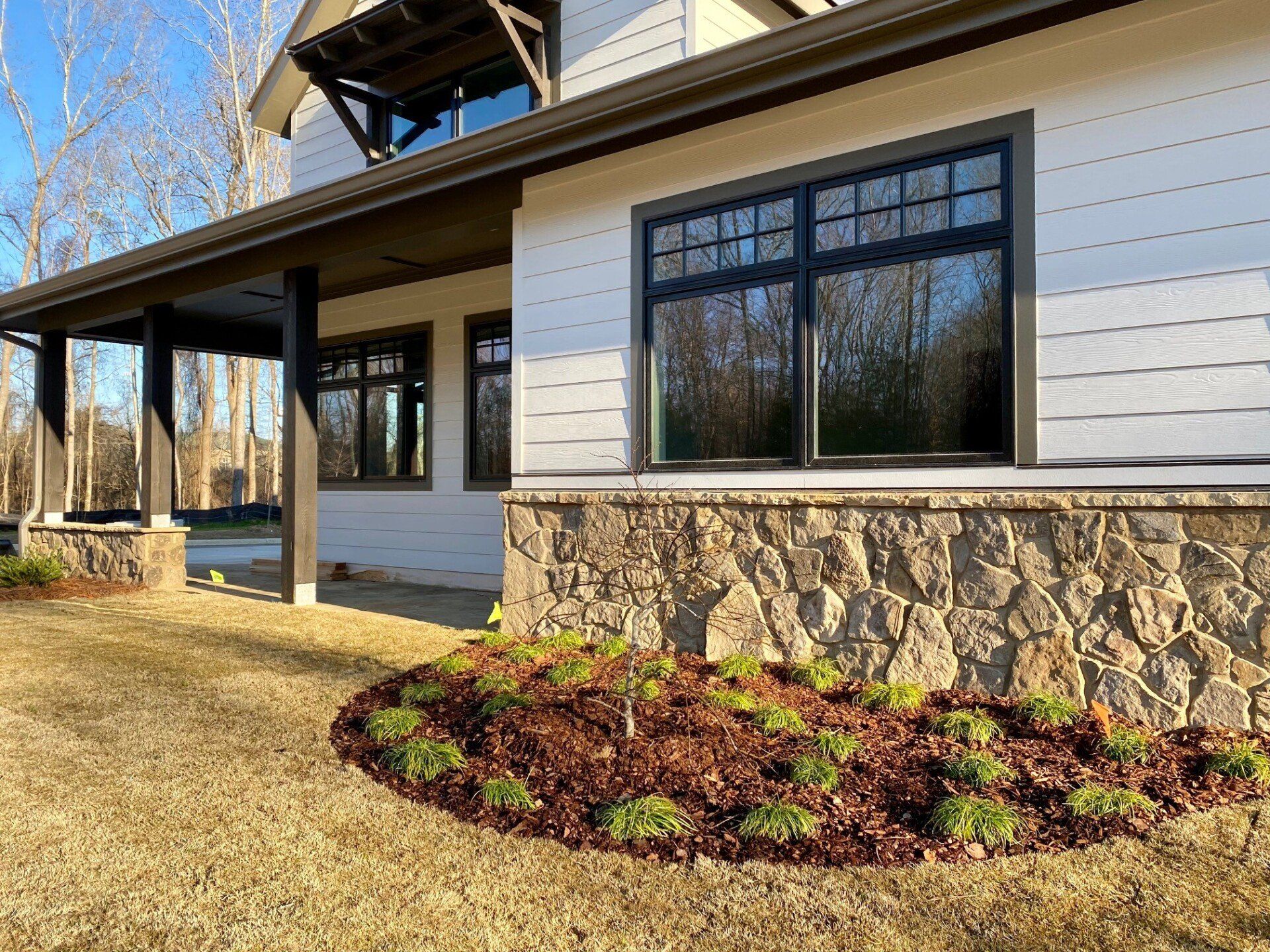 A large white house with a stone wall and a large porch.