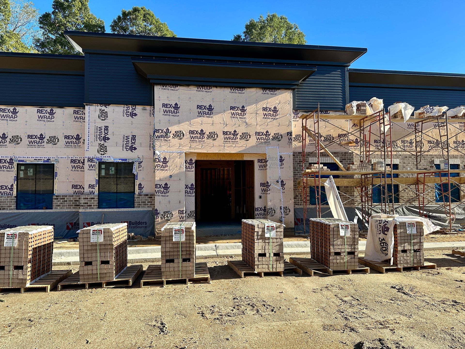 Construction site with a building, scaffolding, and stacks of bricks.
