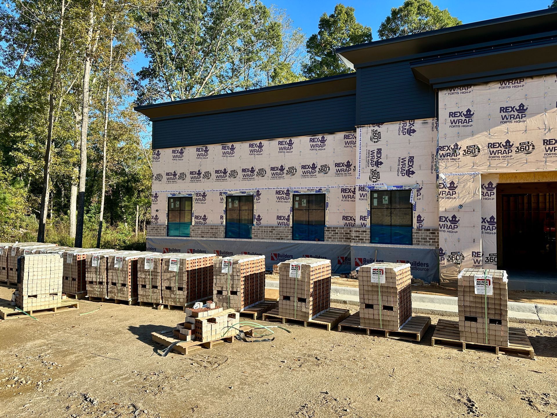 A construction site with a lot of gravel and trees in the background.