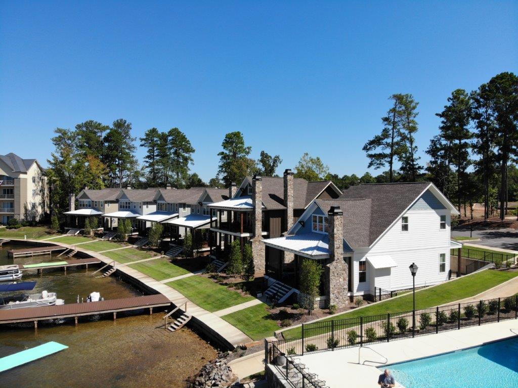A large swimming pool is surrounded by houses and trees