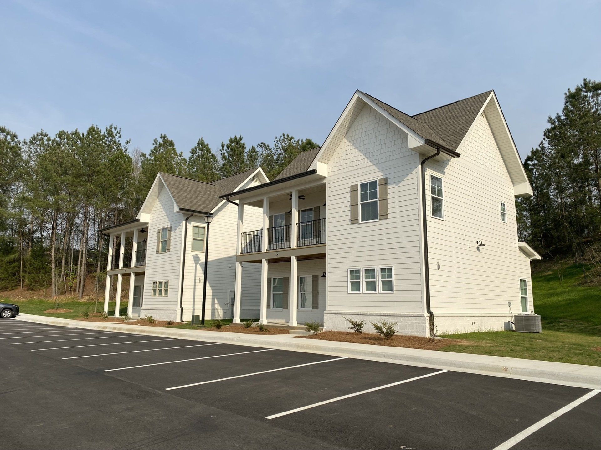 A large white house with a parking lot in front of it