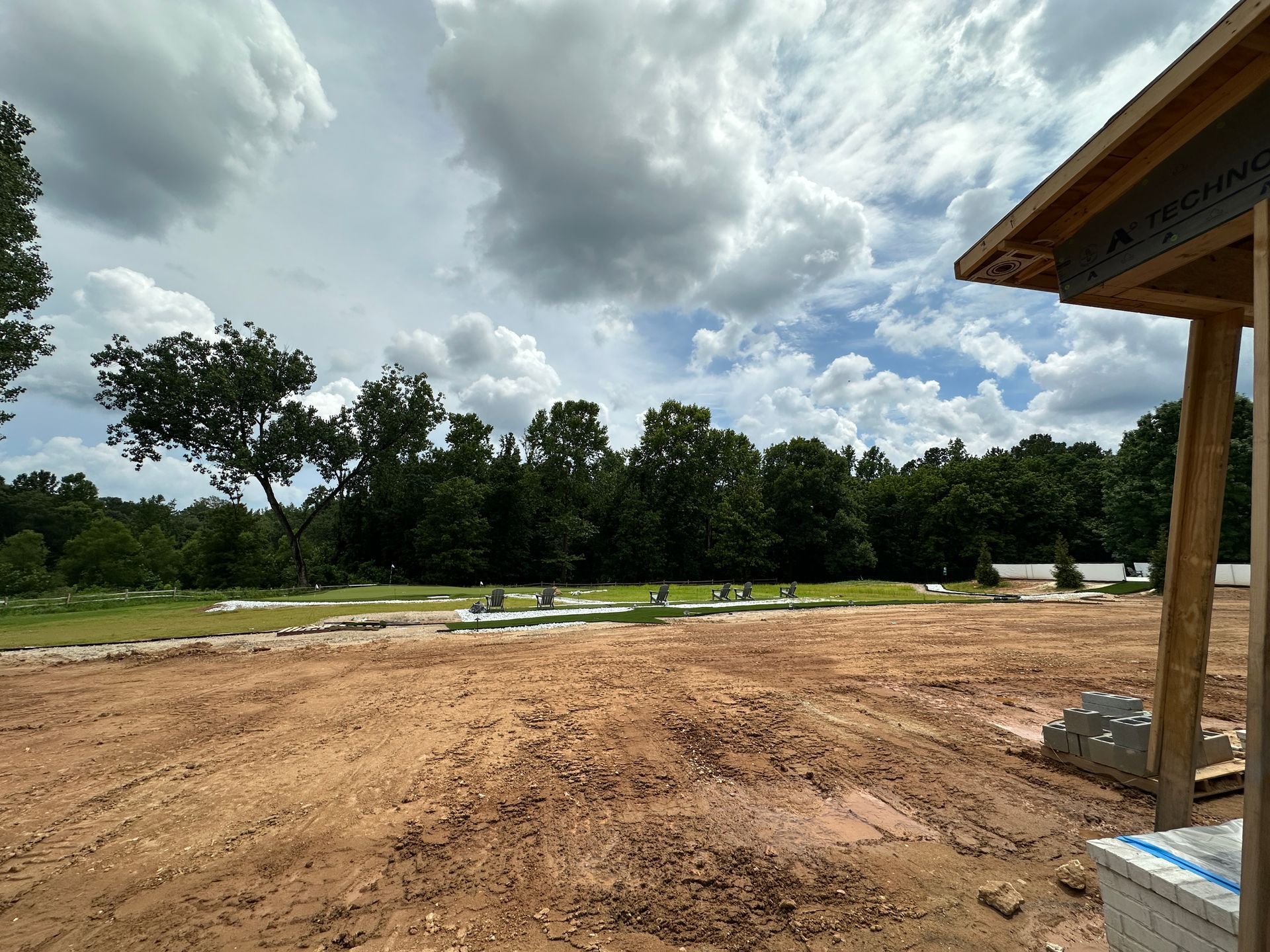 A dirt field with trees in the background and a cloudy sky