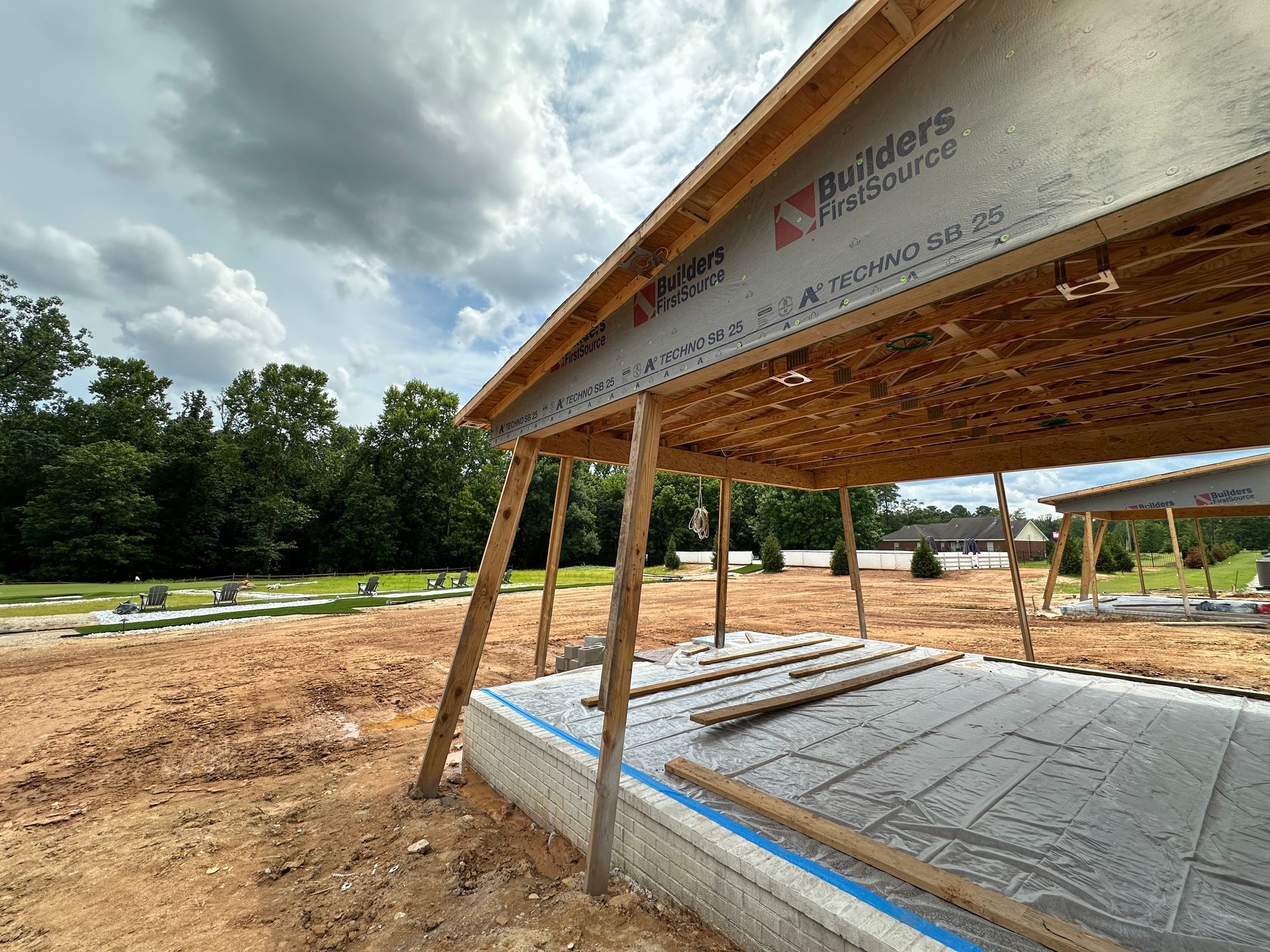 A wooden structure is being built in a dirt field.