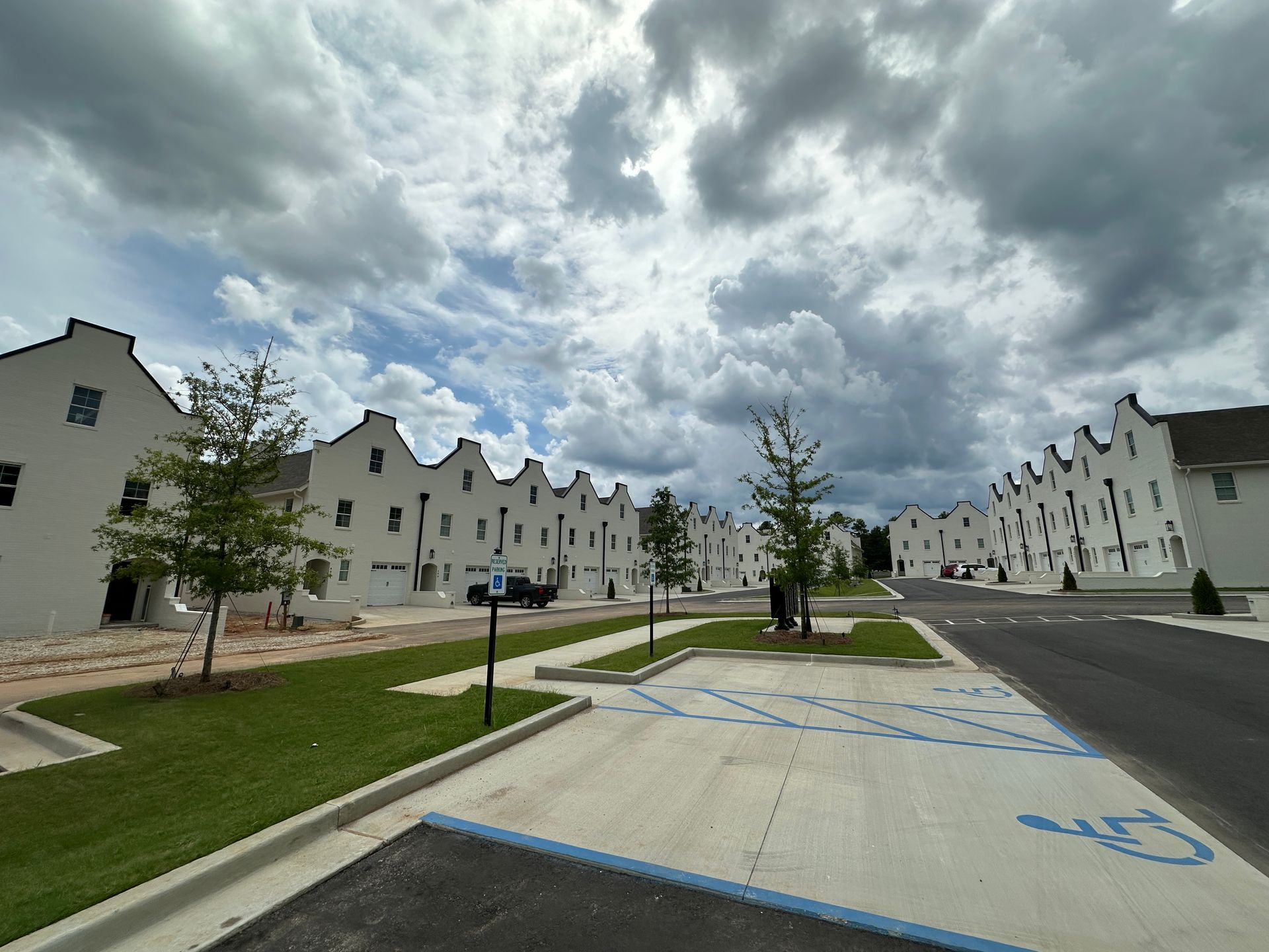 A row of white houses with a handicapped parking spot in front of them.
