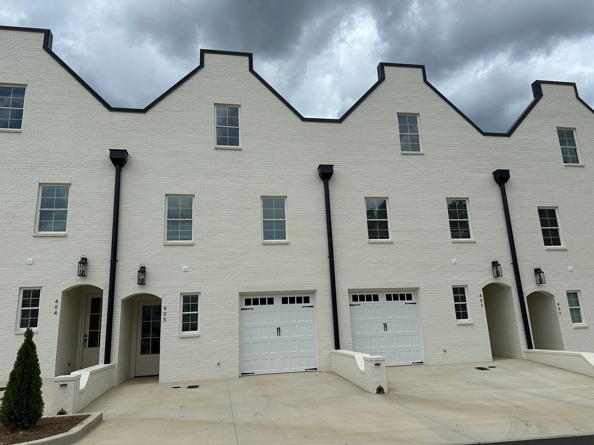 A row of white houses with black trim and gutters
