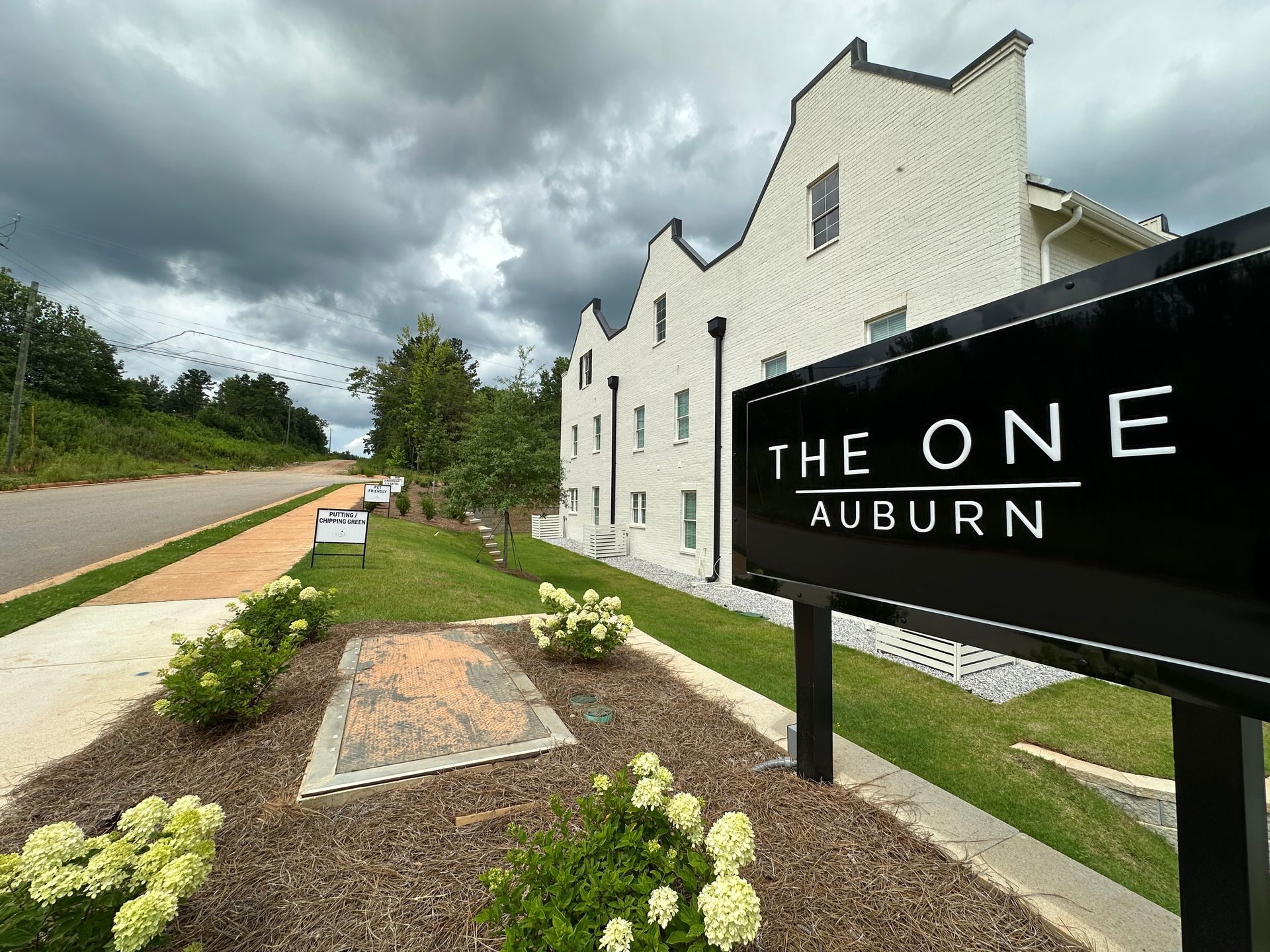 A sign for the one auburn is in front of a white building.