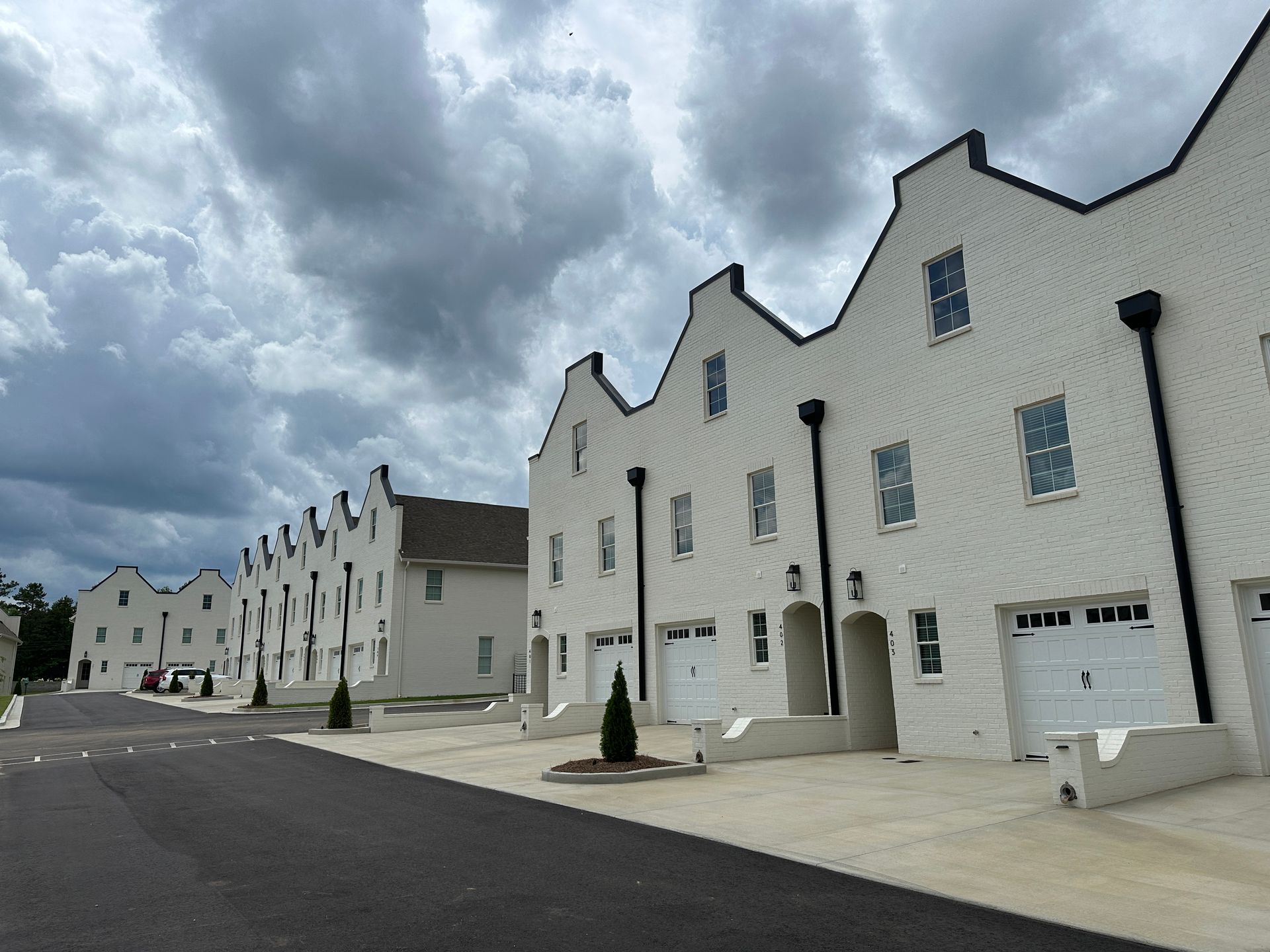 A row of white houses with black trim are lined up next to each other on a cloudy day.