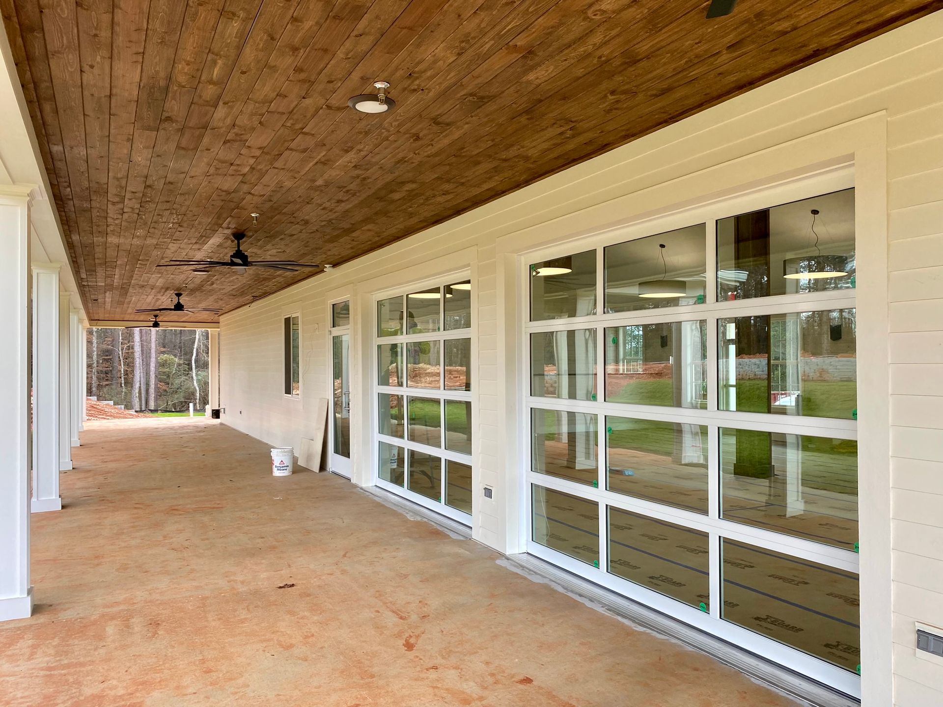 A large porch with a wooden ceiling and a lot of windows.