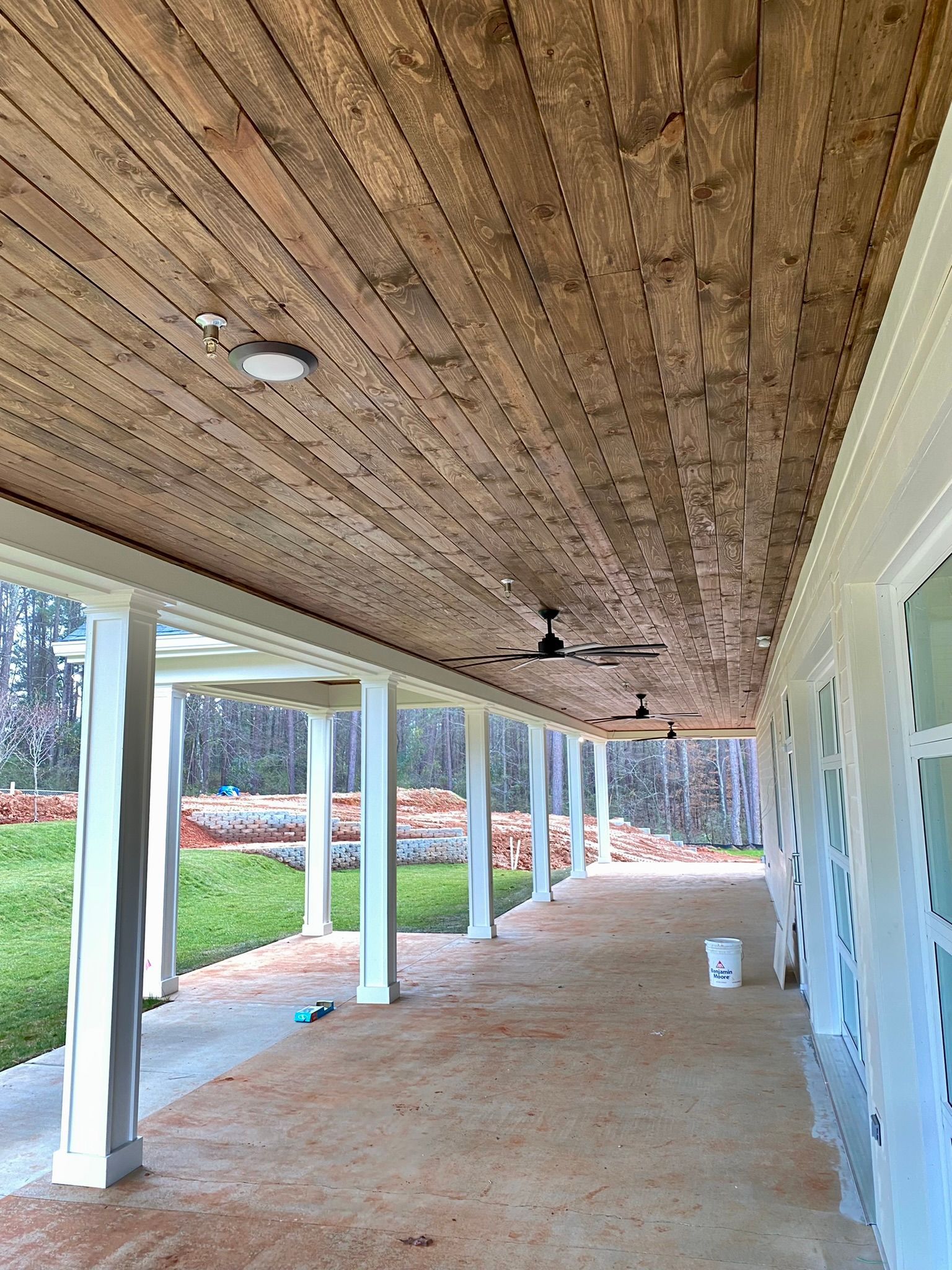 A long porch with a wooden ceiling and ceiling fans.