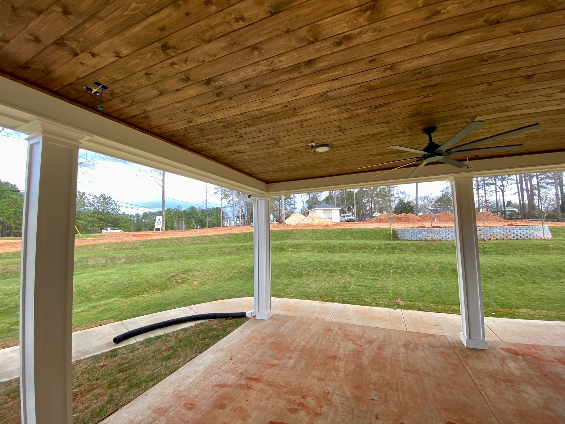 A porch with a wooden ceiling and a ceiling fan.