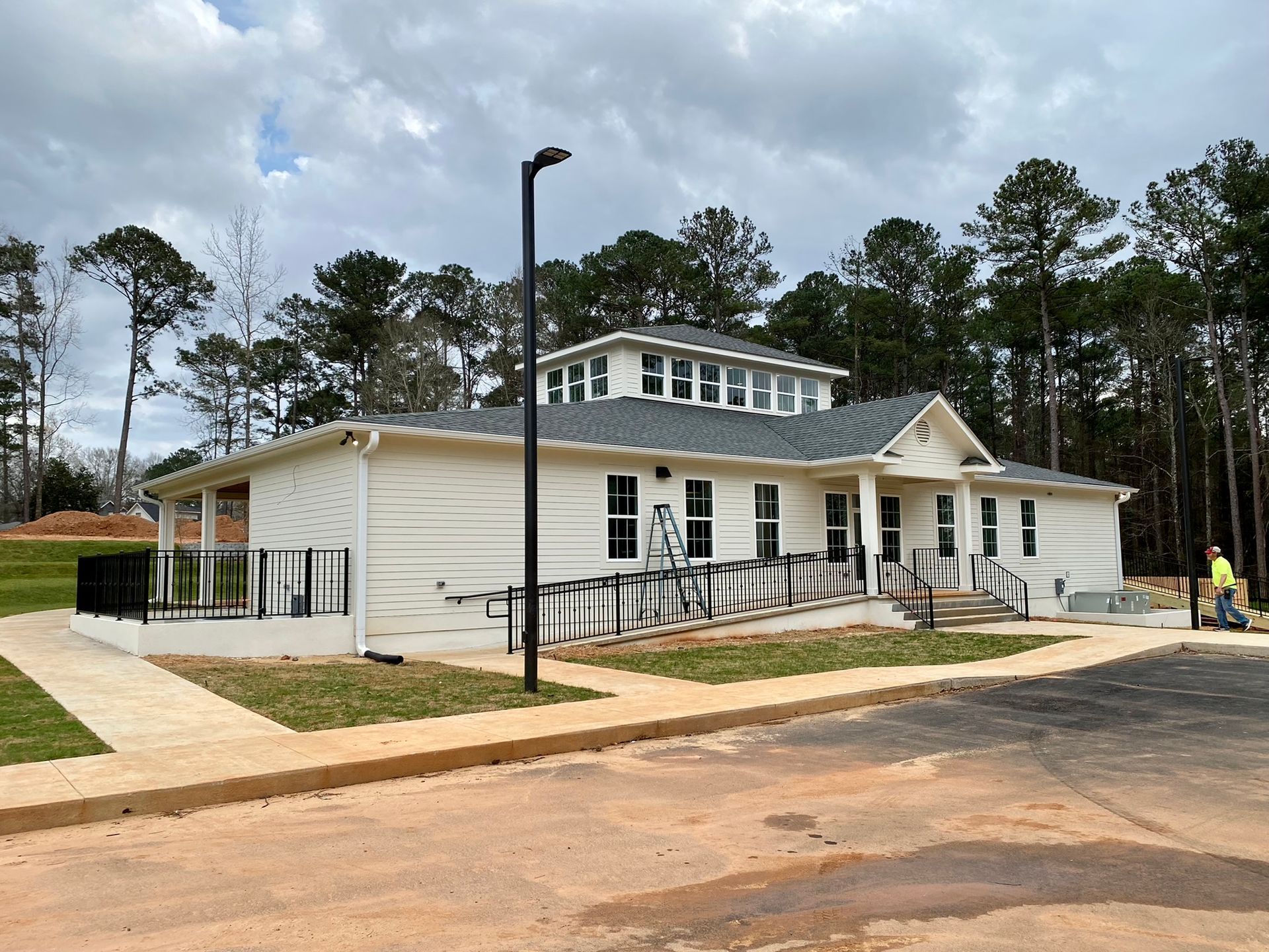 A white house with a gray roof is being built in the woods.