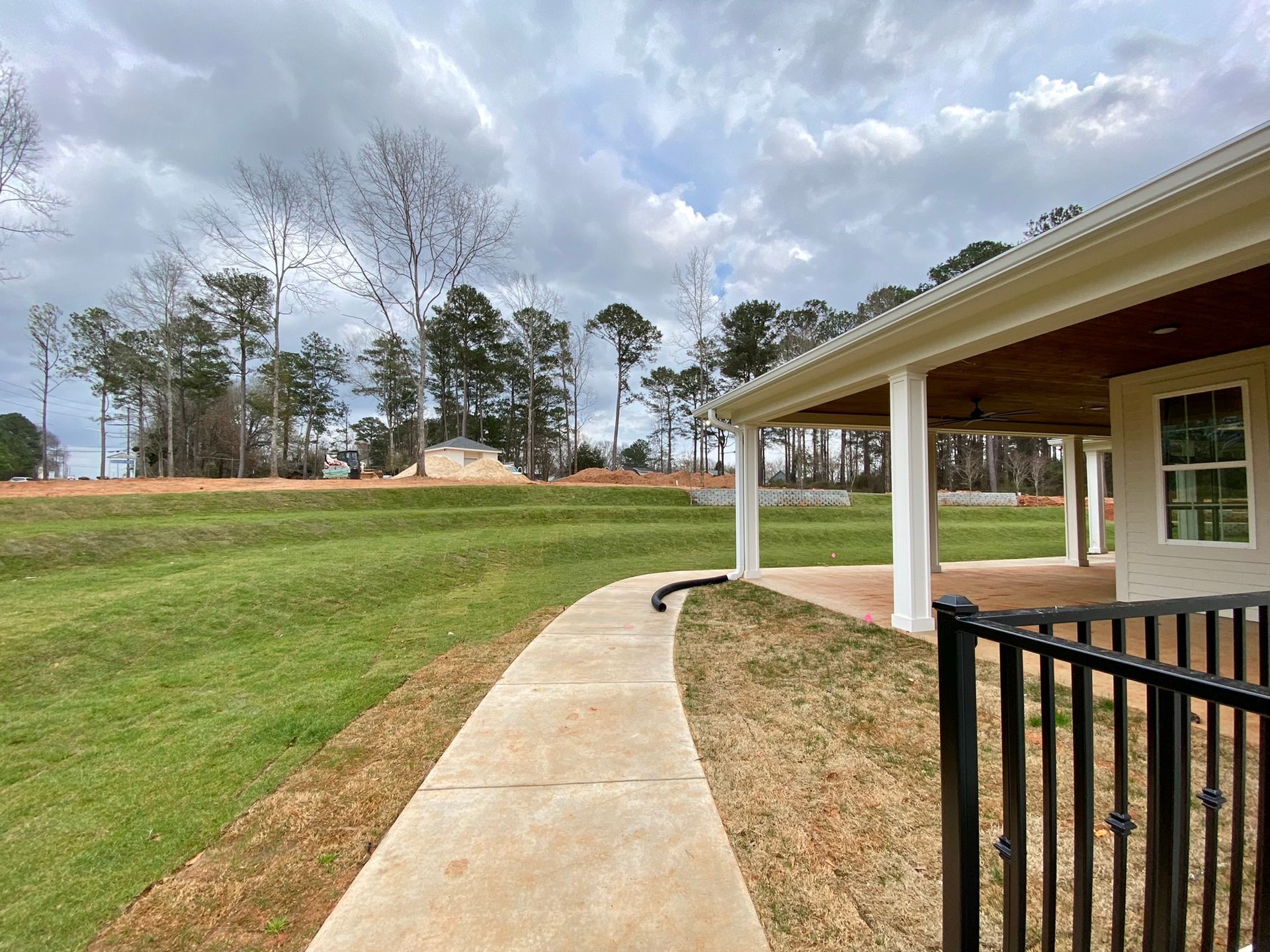 A walkway leading to a house with a porch and a fence.