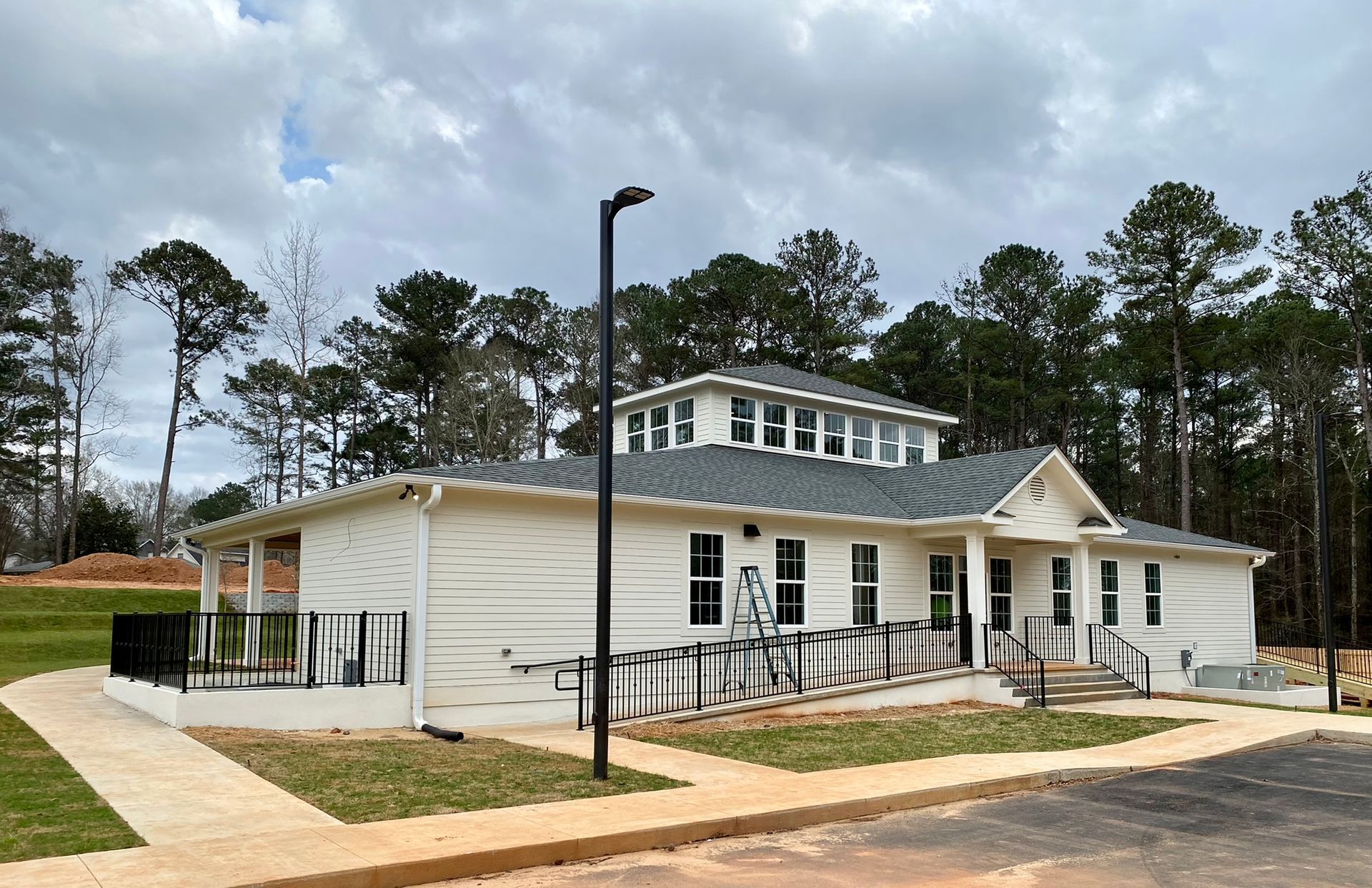 A large white house with a gray roof is surrounded by trees.