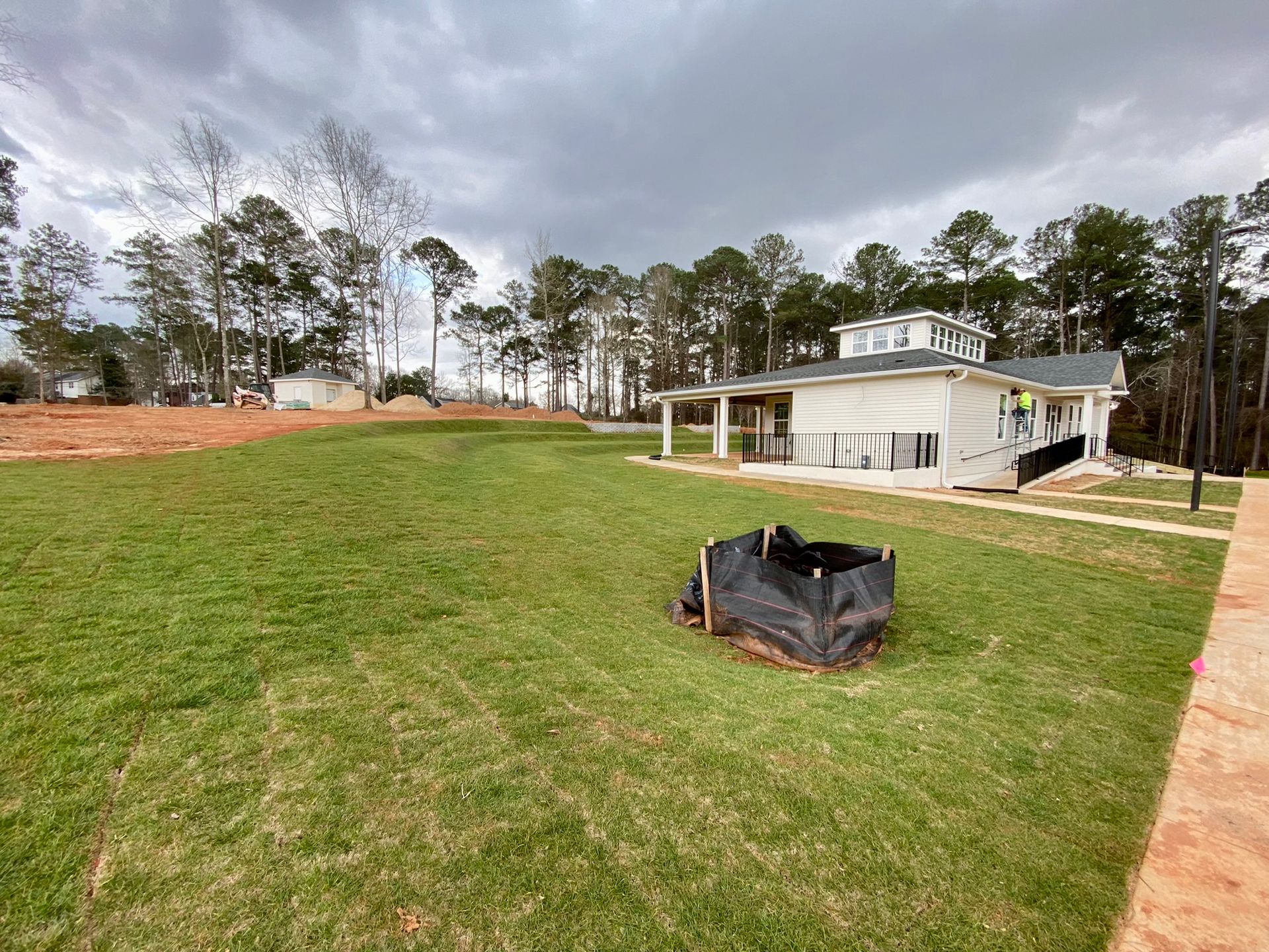 A large lush green field with a house in the background.