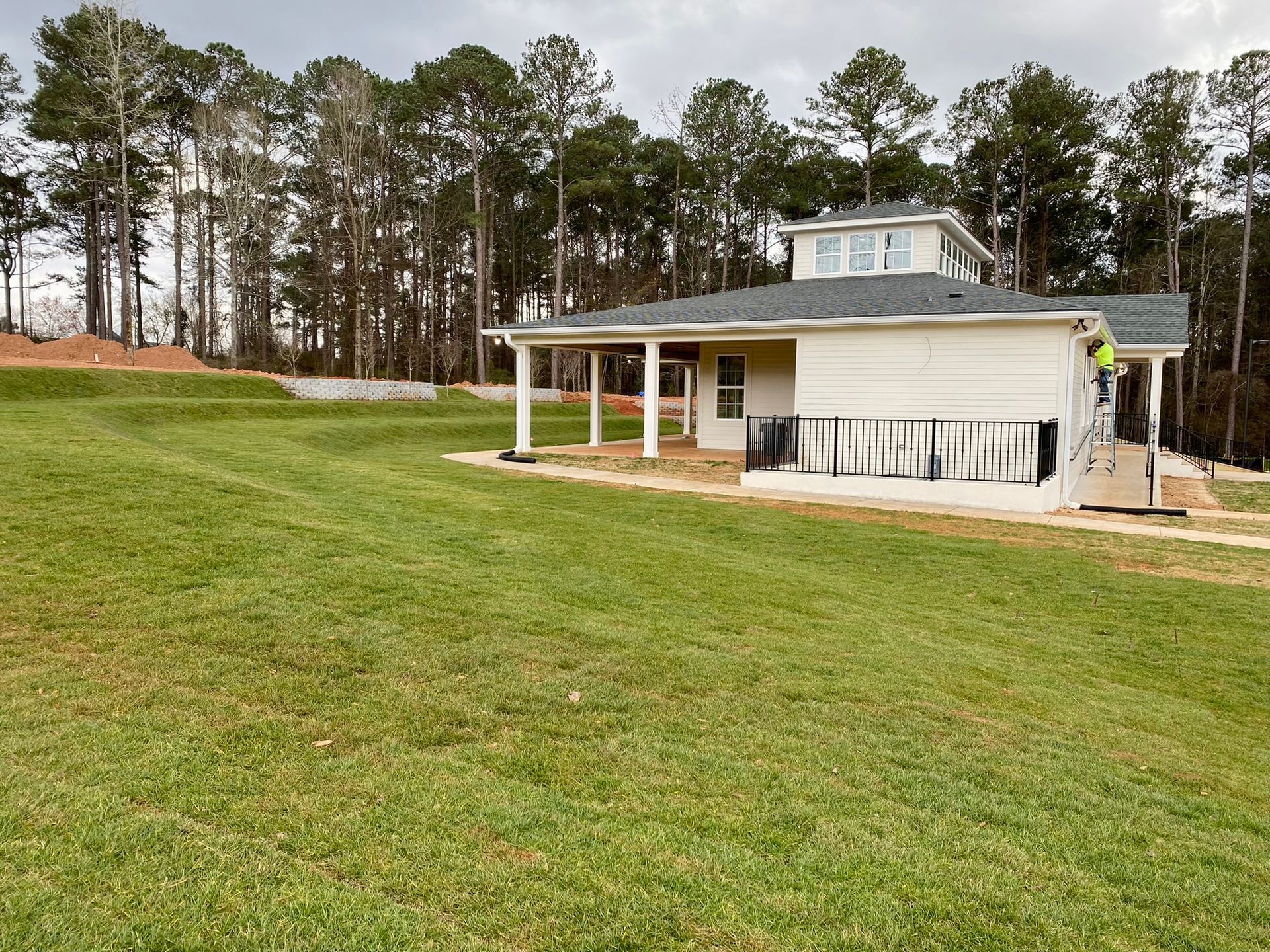 A white house sits in the middle of a lush green field