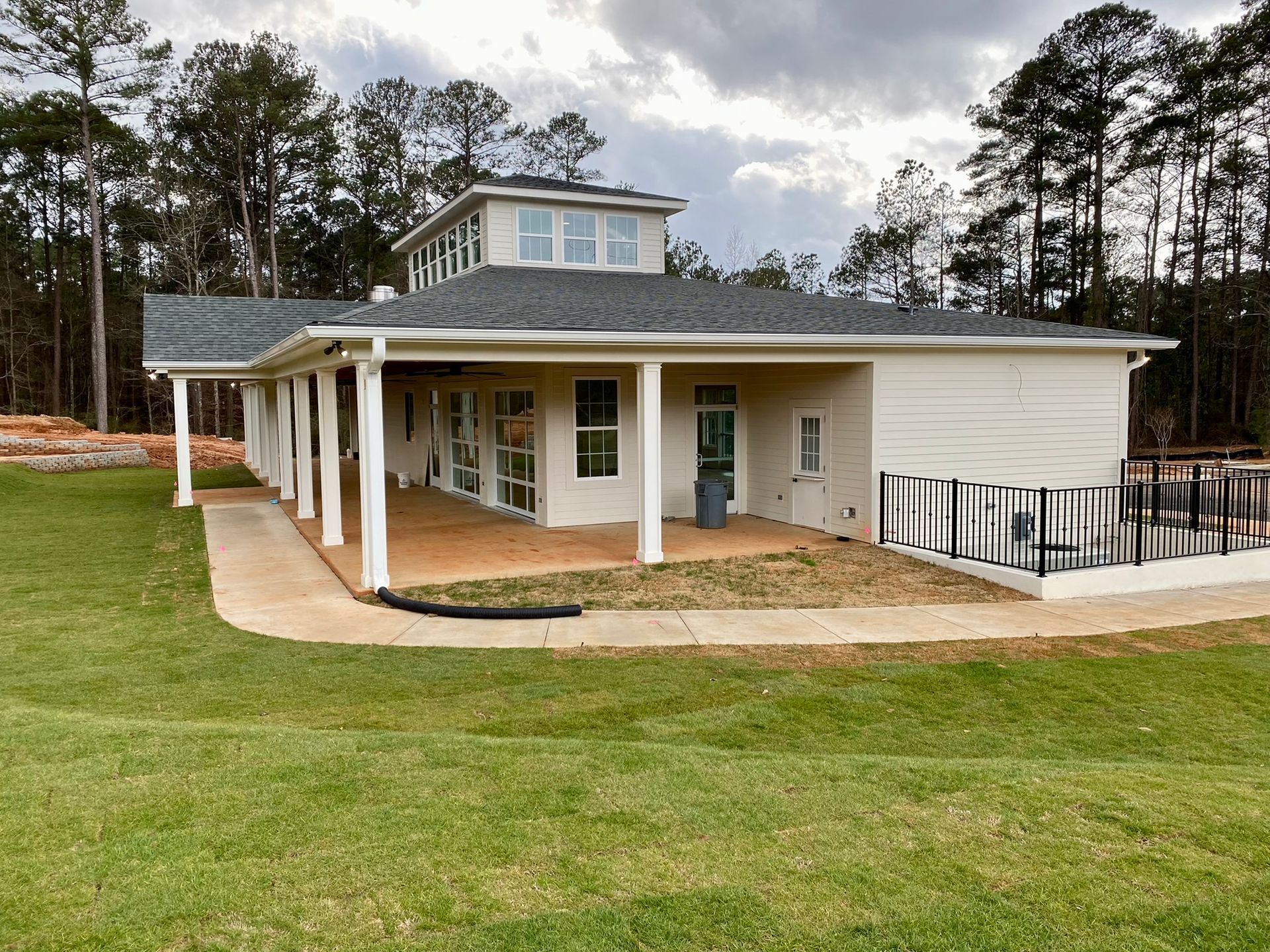 A large white house with a porch and a walkway surrounded by trees.