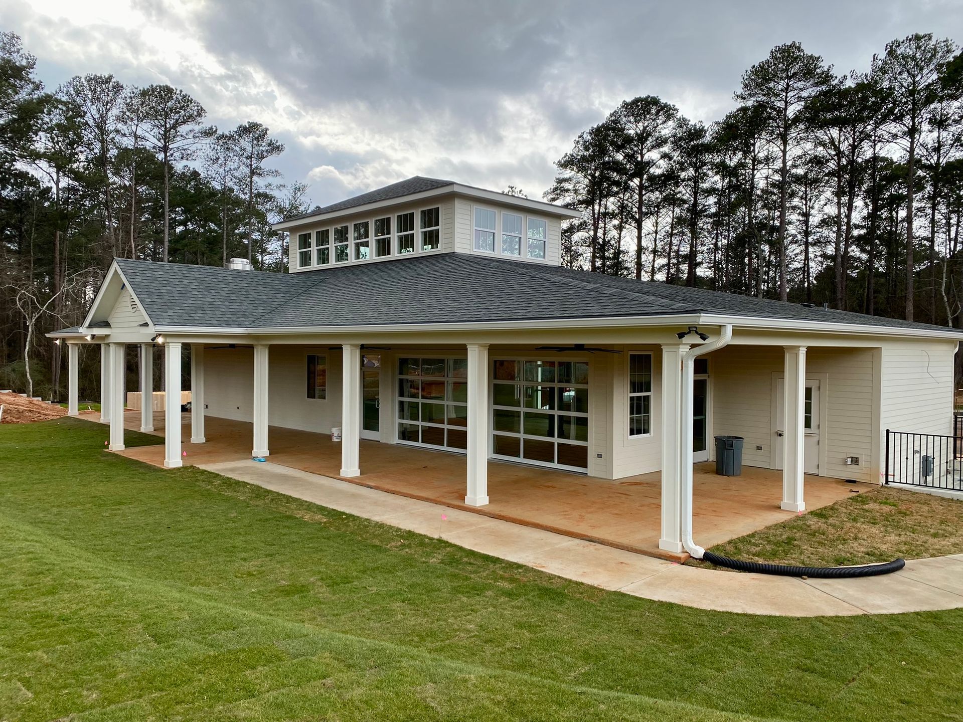 A large white house with a porch and trees in the background.