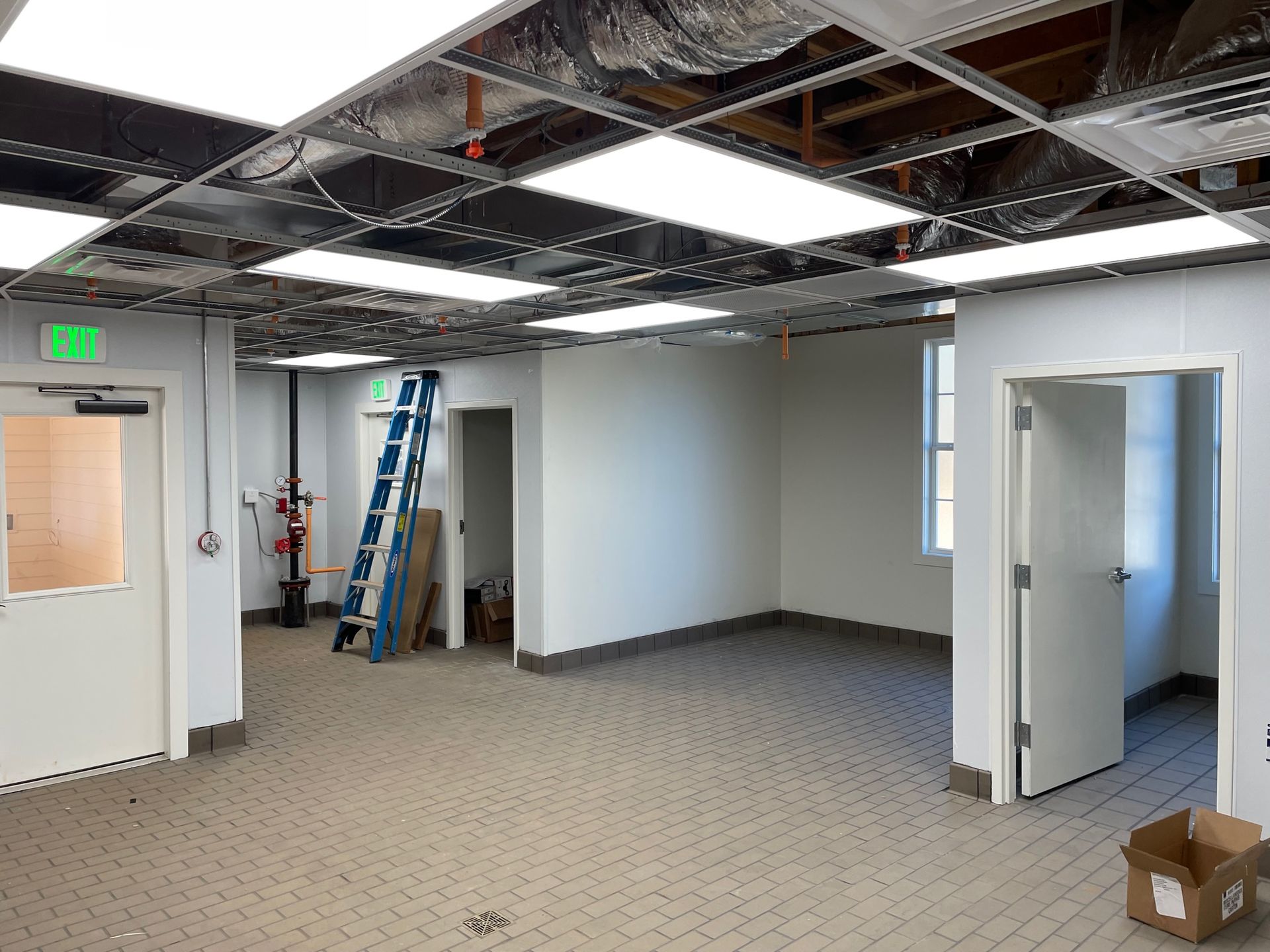 An empty room with a green exit sign on the ceiling