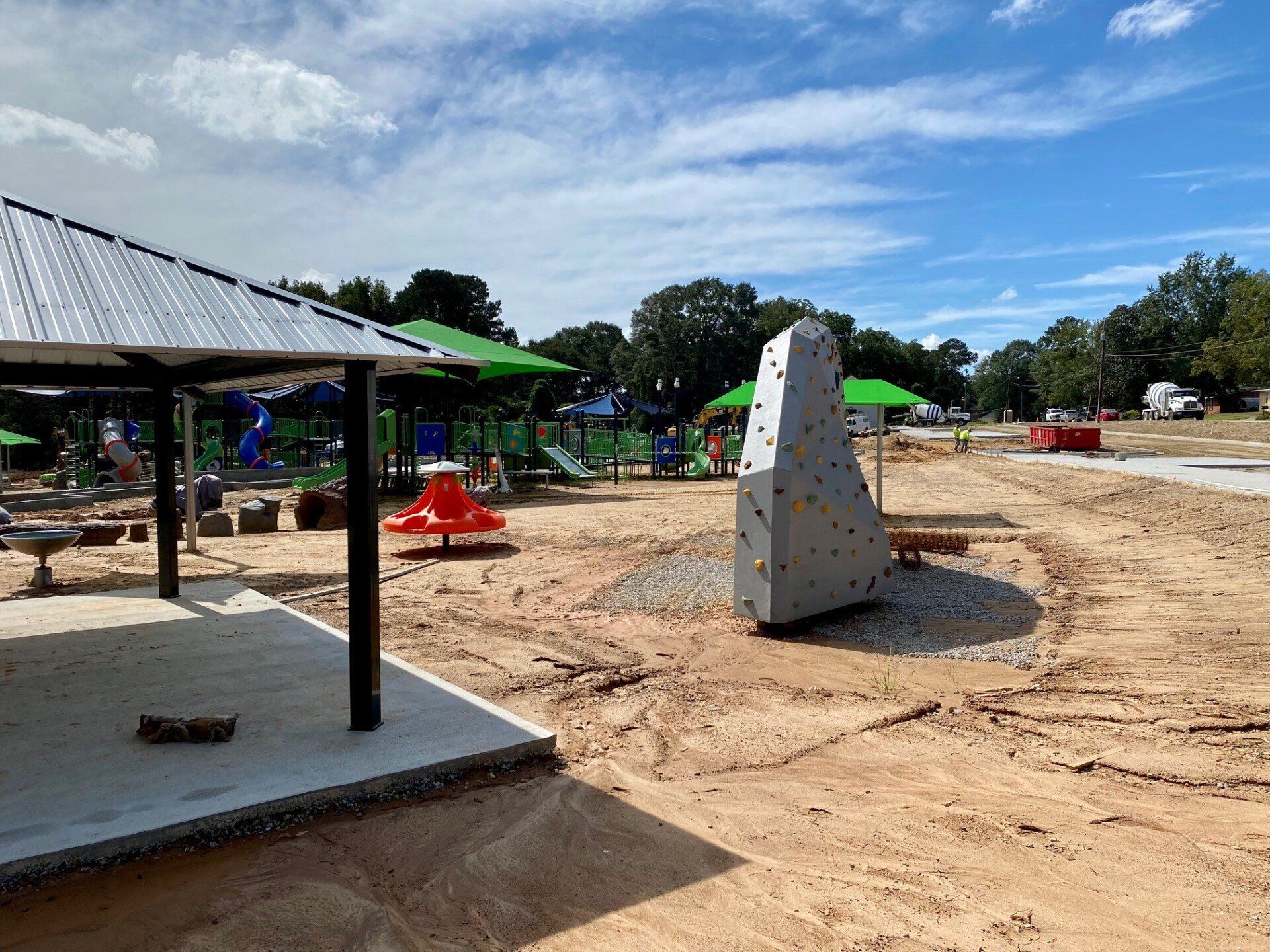 A large rock climbing wall is sitting in the middle of a playground.