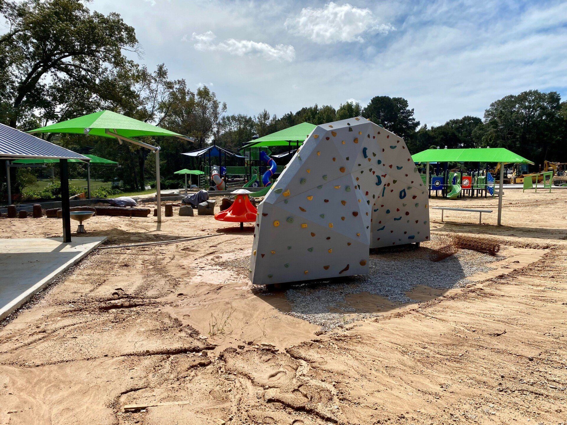 A climbing wall is sitting in the middle of a playground.
