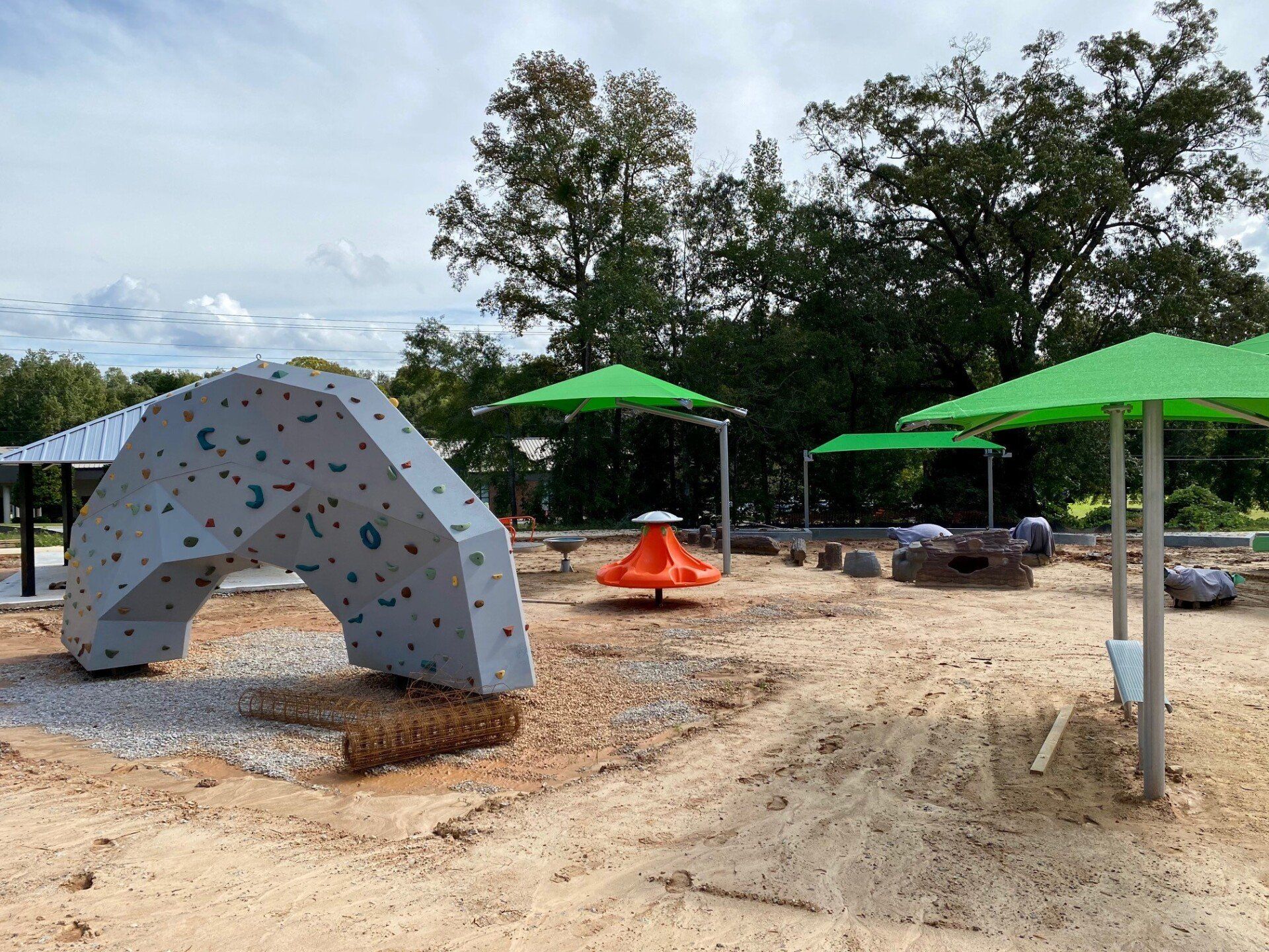 A playground with green umbrellas and a climbing wall
