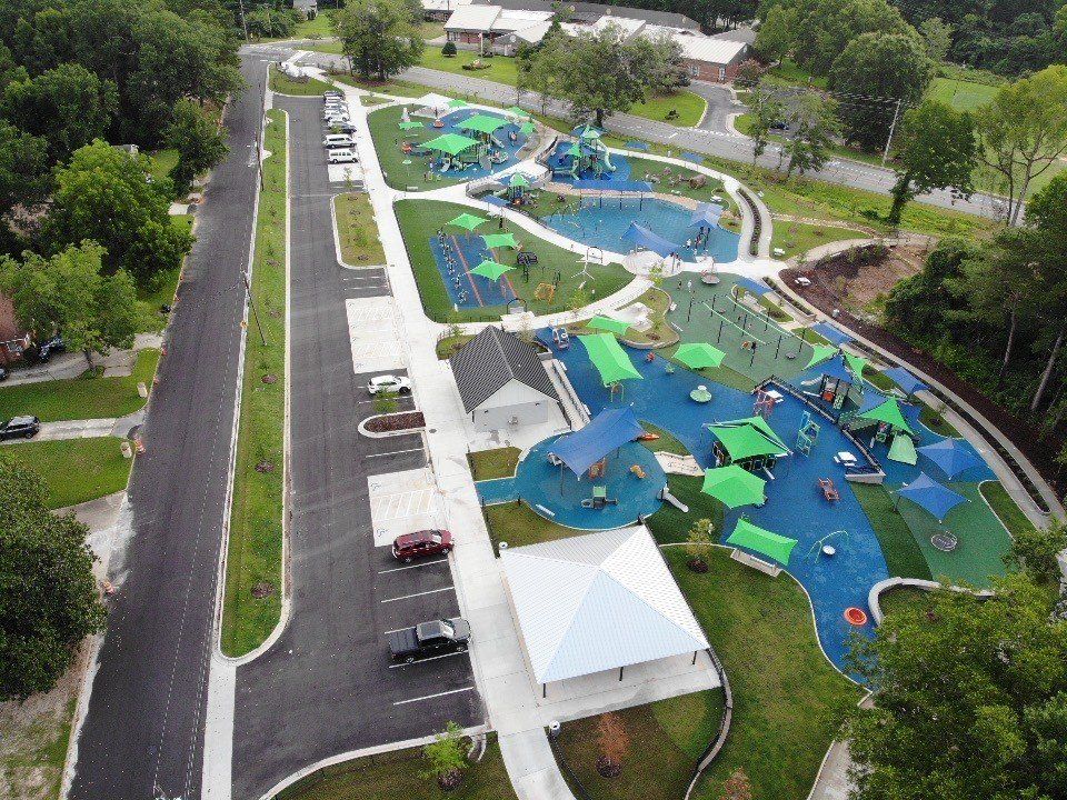 An aerial view of a park with a playground and umbrellas.