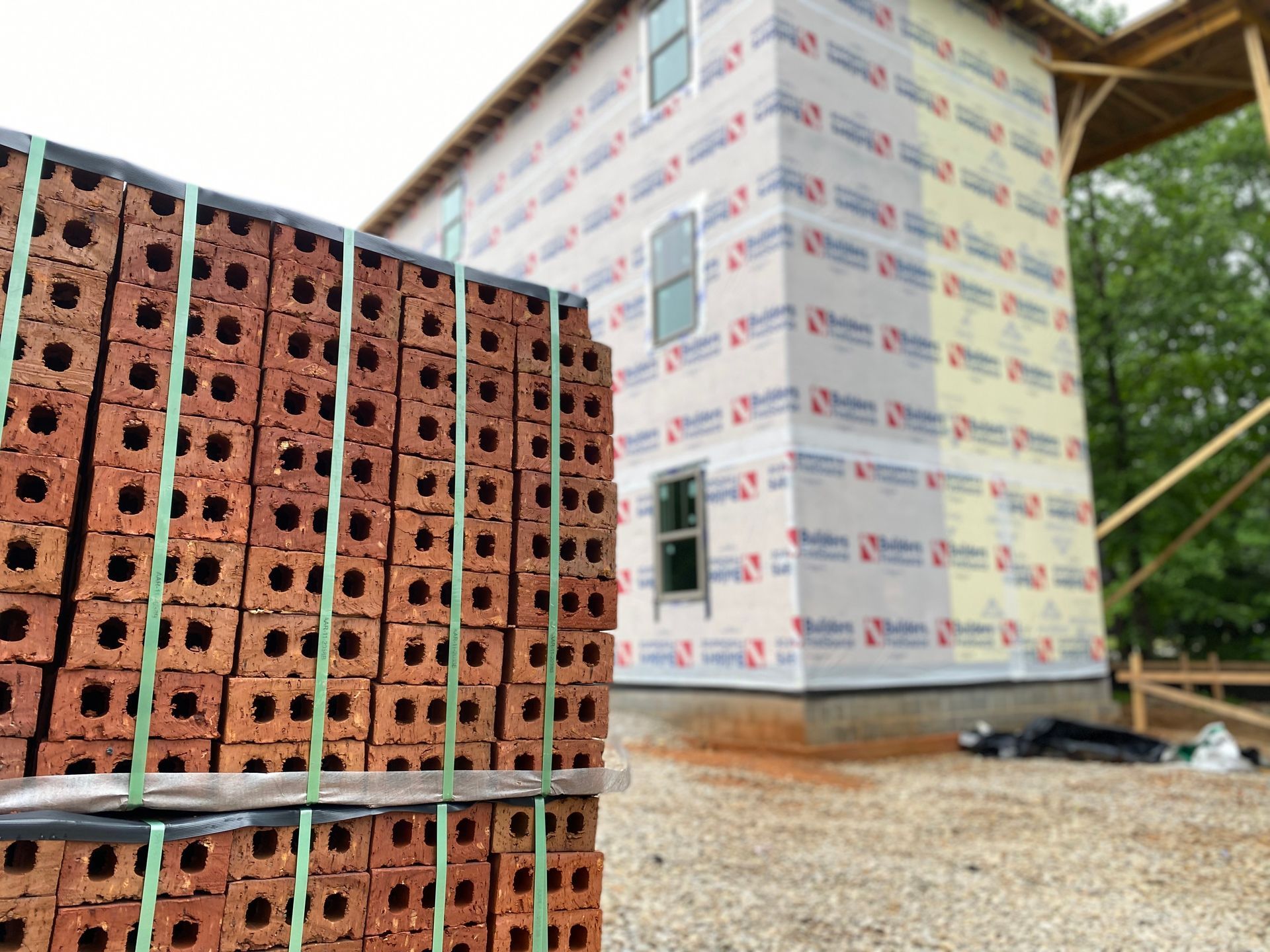 A stack of bricks is sitting in front of a building under construction.