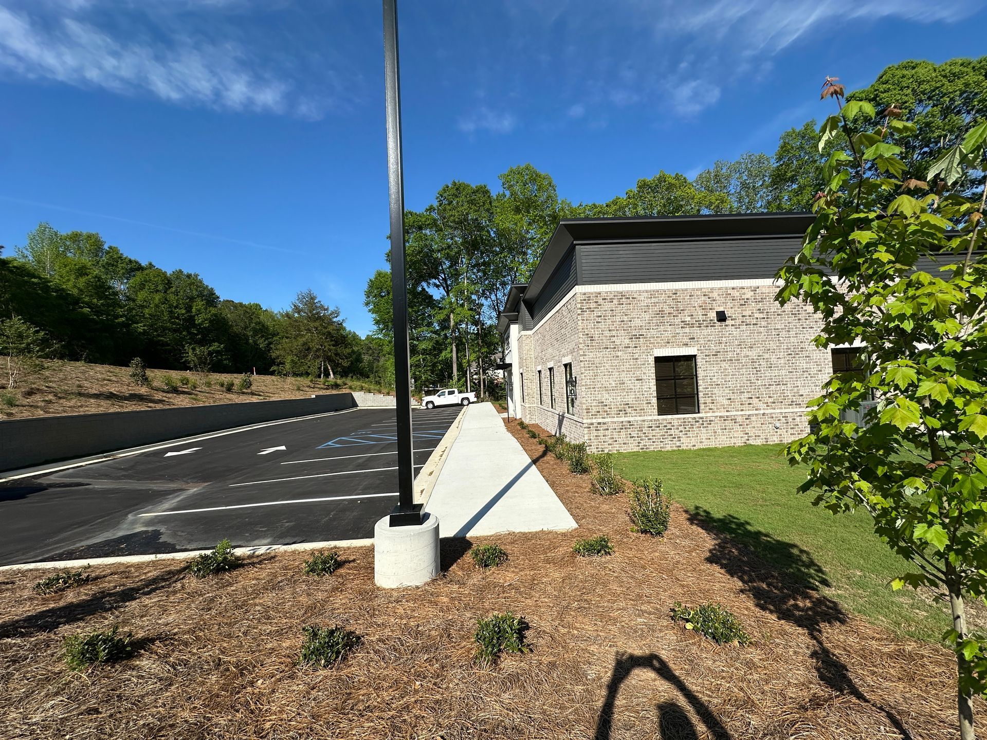 A new parking lot with a handicap spot adjacent to a stone-faced building under a bright blue sky.