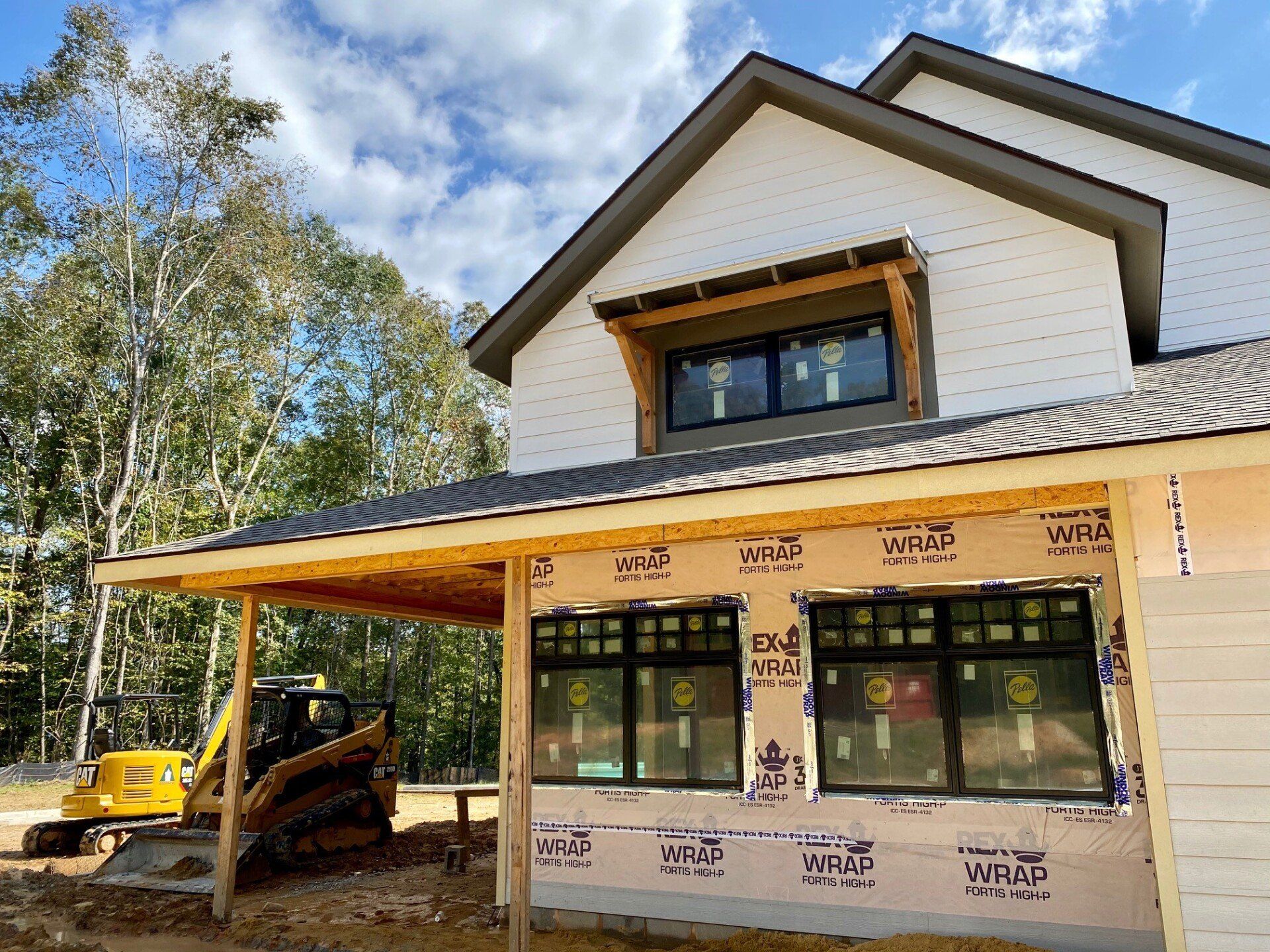 A house under construction with a bulldozer parked in front of it.