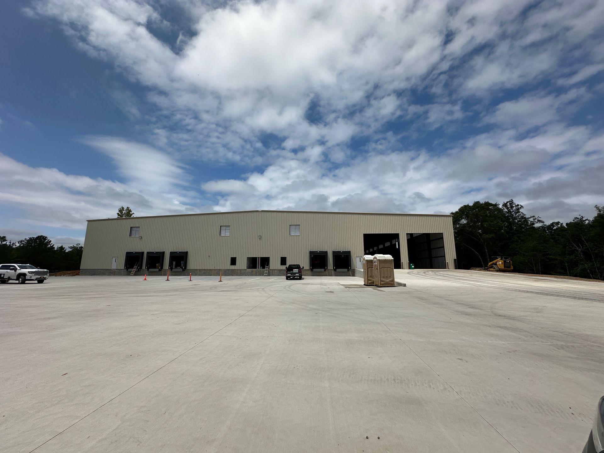 Large industrial building with loading docks and open bay doors under a cloudy sky.