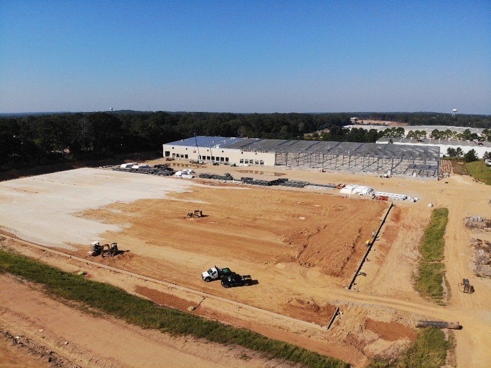 An aerial view of a construction site with a large building in the background