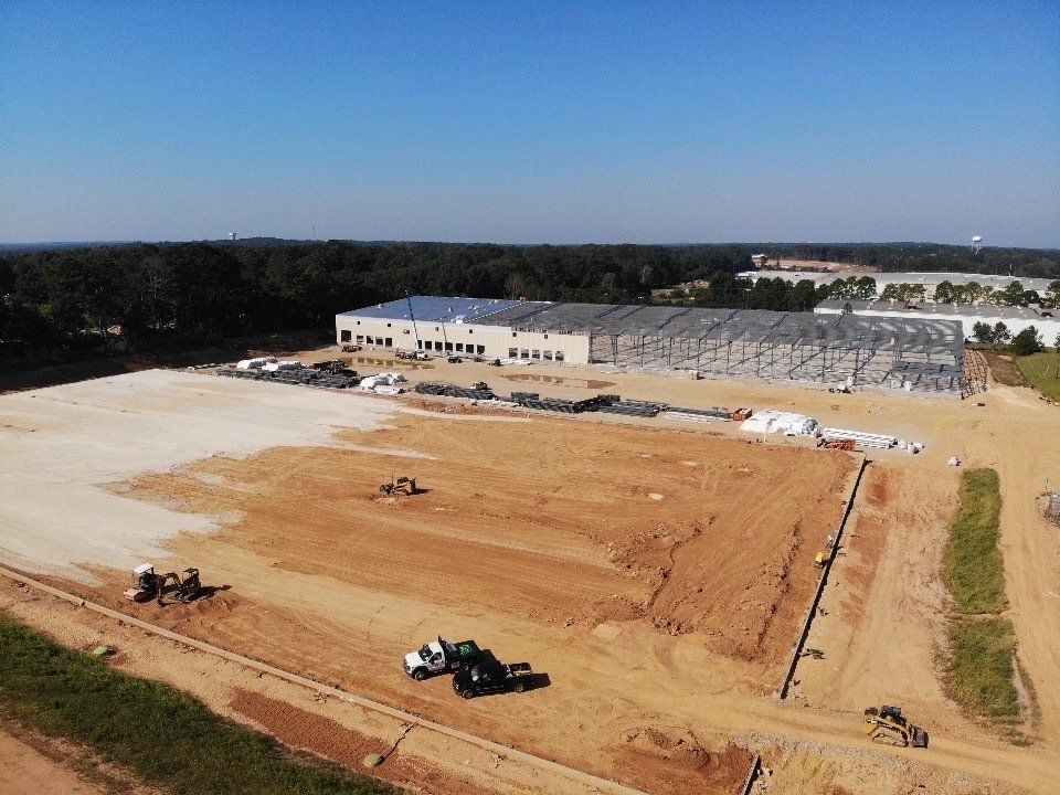 An aerial view of a construction site with a large building in the background