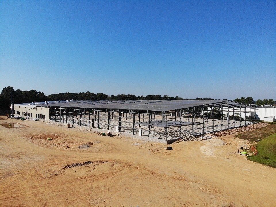 An aerial view of a large building under construction in the middle of a dirt field.