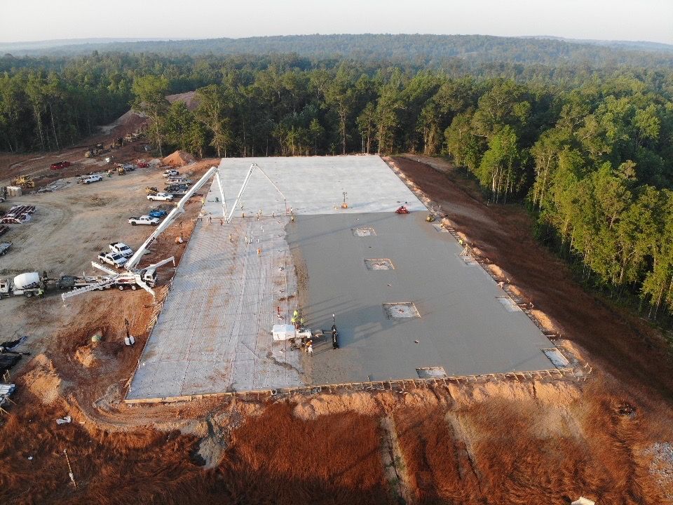 An aerial view of a large building under construction in the middle of a forest.