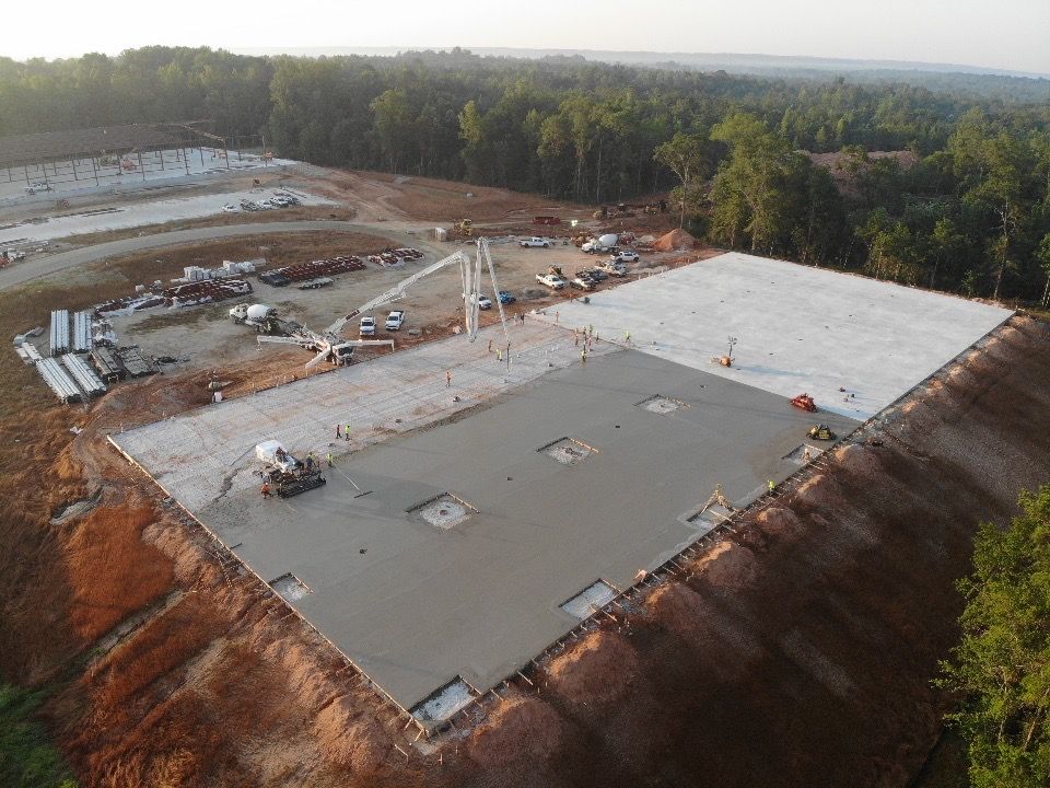 An aerial view of a large concrete structure being built on top of a hill.