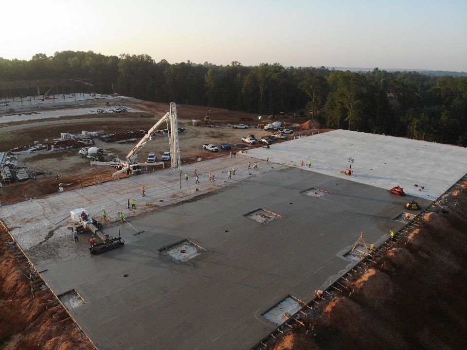 An aerial view of a construction site with a large concrete slab being poured.