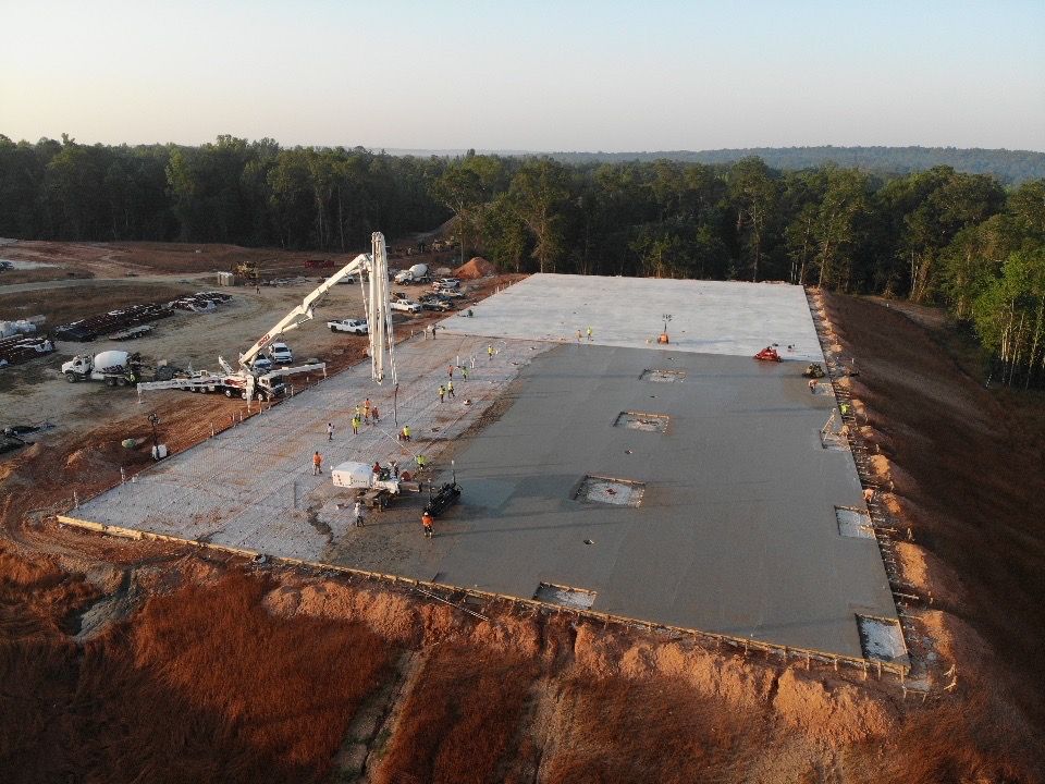 An aerial view of a large building under construction in the middle of a forest.