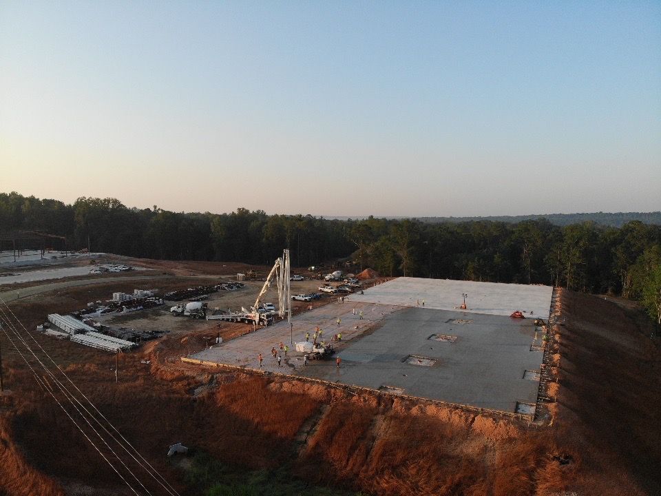 An aerial view of a construction site with a lot of dirt and trees in the background.