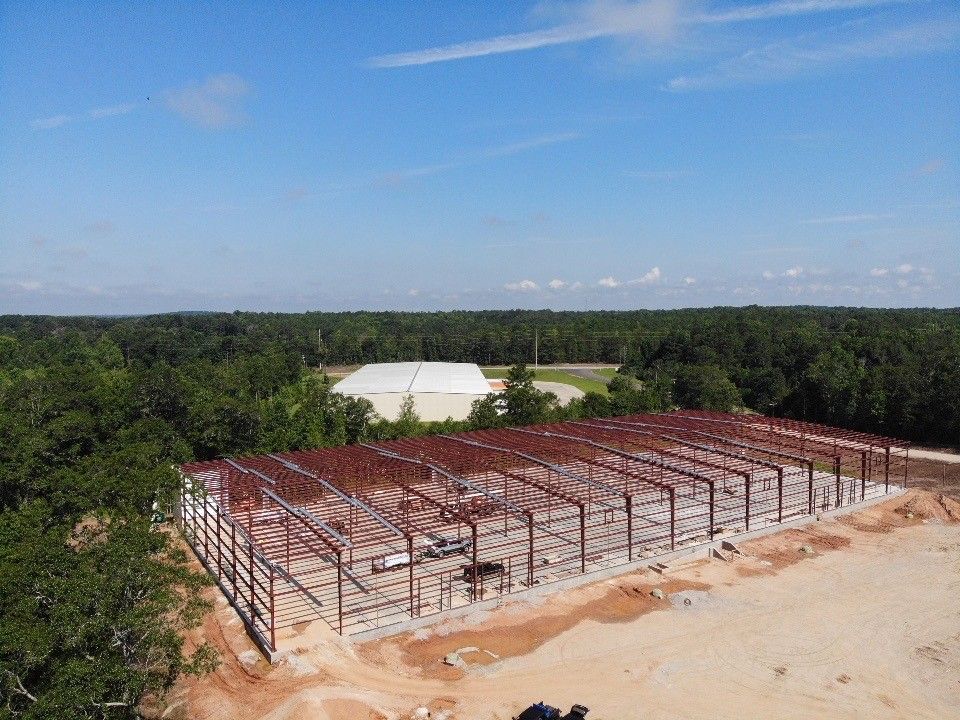 An aerial view of a building under construction in the middle of a forest.