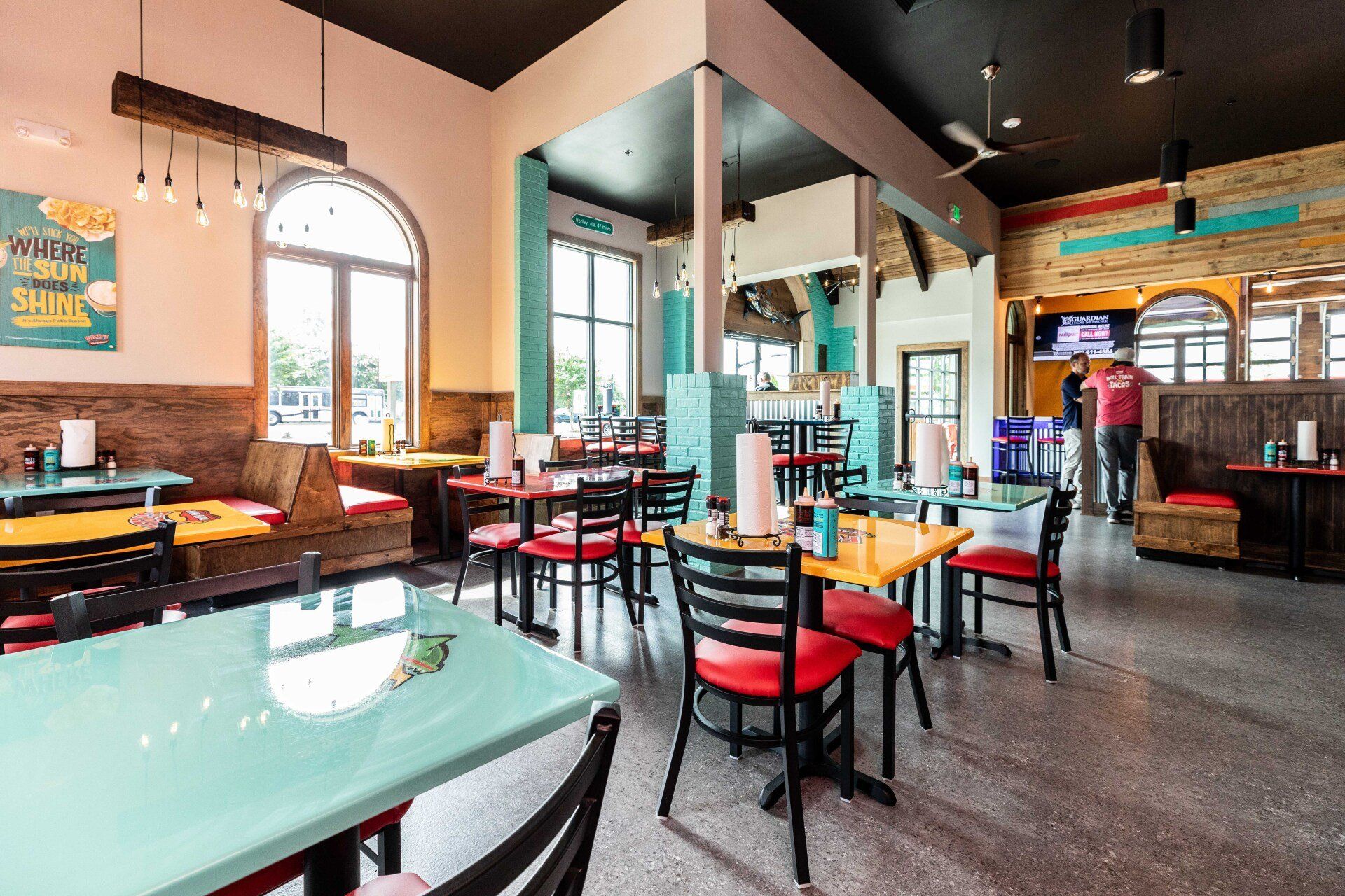 A restaurant with tables and chairs and a man standing in the background.