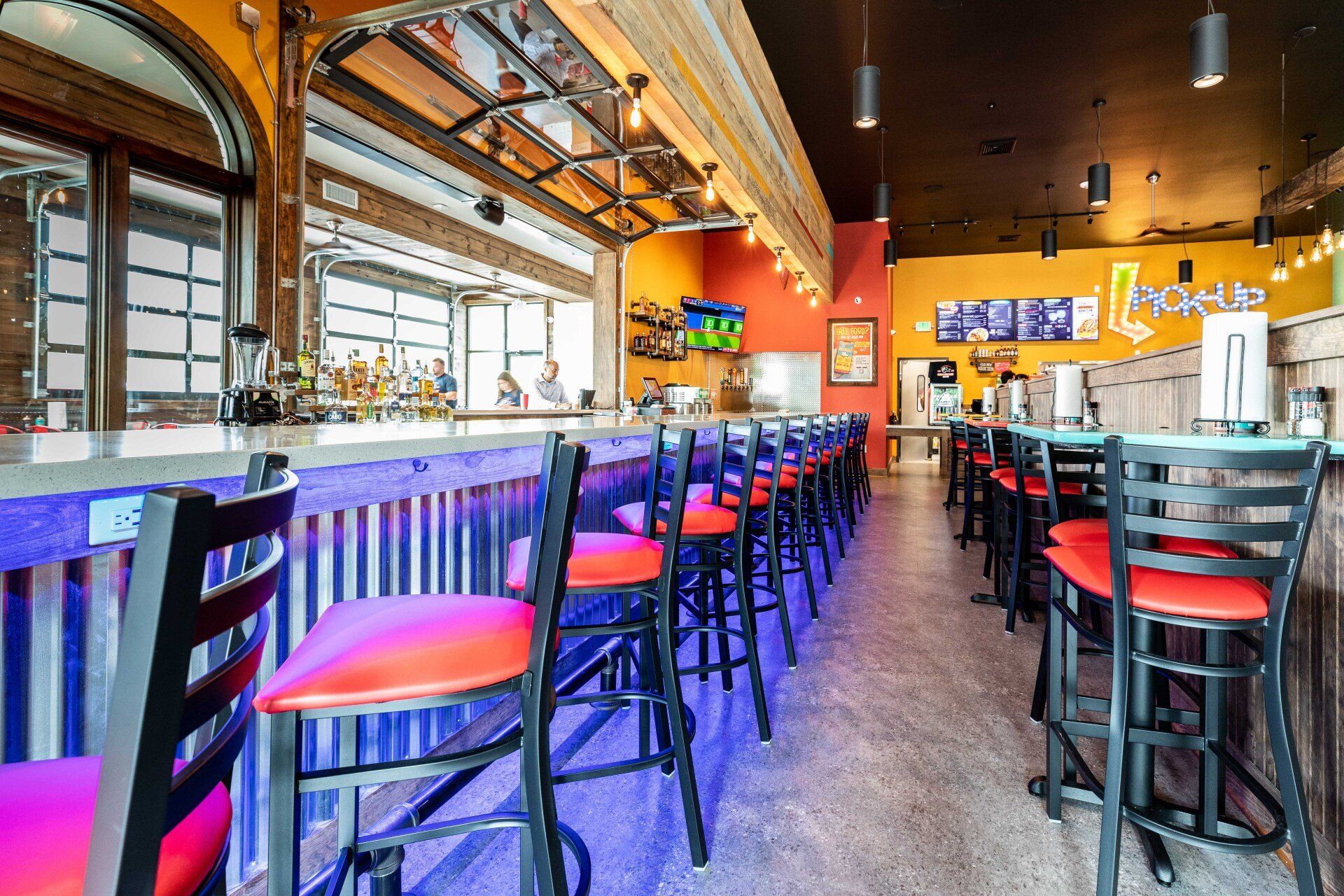 A restaurant with a long bar and tables and chairs